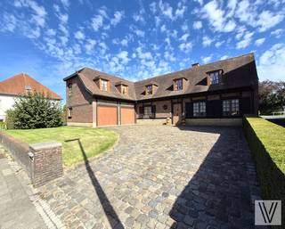 Centraal gelegen ruime verzorgde villa op 737 m², bestaande uit de inkomhal met toilet, (slaap)kamer/polyvalente ruimte,  woon/leefruimte (alle met inbouwspots) met aansluitend de nieuwe keuken, zonnige veranda, berging/wasruimte en 2de toilet, dubbele garage, tuin met terras en bijgebouw met sauna en douche.. Op het verdiep zijn er maar liefst 5 slaapkamers telkens met inbouwkasten en lavabo. Zolder. Houten ramen met dubbel glas. De woning is ingericht met kwalitatieve materialen. Open haard. Kelder. Zonnepanelen. Er is plaats voor 4 auto's op de oprit.