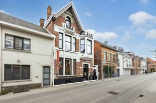 <p><strong>Op een centrale locatie in het hart van Kasterlee bevindt zich dit uitzonderlijk karaktervol eigendom, momenteel gekend als Boudoir D’or. Dit stijlvolle burgerhuis combineert een authentieke uitstraling met tal van mogelijkheden voor wonen, werken en ondernemen. De statige voorgevel met markante erker geeft het eigendom een sterke visibiliteit en unieke uitstraling in het straatbeeld. Binnenin zorgen bewaarde karakterelementen, zoals parketvloeren, glas-in-loodramen, hoge plafonds, rozetten en moulures, voor een warme sfeer. Dankzij de indeling en centrale ligging leent dit eigendom zich uitstekend voor diverse invullingen: handelspand met woonst, kantoorruimte, praktijkruimte, showroom, vrij beroep of een stijlvolle combinatie van wonen en werken. De authentieke architectuur geeft elke professionele activiteit extra uitstraling. Bovendien geniet het eigendom van een uitstekende bereikbaarheid, met voorzieningen in de directe omgeving en parkeermogelijkheden op eigen terrein, achteraan bereikbaar via de Markt. Dit vormt een belangrijke troef voor bewoners, klanten en bezoekers.<br /><br /></strong><span>Gelijkvloerse verdieping</span>: Op de gelijkvloerse verdieping wordt men verwelkomd in een stijlvolle inkomhal met prachtige authentieke trap. Het voorste gedeelte is momenteel ingericht als kledingszaak en geniet, dankzij de centrale ligging en zichtbaarheid in het straatbeeld, van een sterke commerciële uitstraling.<br /><br />Achterliggend bevindt zich het private woongedeelte met gezellige woonkamer en aansluitende keuken. De indeling laat toe om wonen en werken comfortabel te combineren. Vanuit dit achterste gedeelte is er via een vaste trap toegang tot de bovenverdieping, zonder door de kledingszaak te moeten gaan. Zo ontstaat een duidelijke scheiding tussen het professionele gedeelte vooraan en het private gedeelte achteraan.<br /><br />De woonkamer beschikt over een open haard op gas. De keuken is uitgerust met een Godin kookvuur op gas, extra oven, koelkast en diepvries. Langs de achterzijde is er toegang tot de tuin. Verder biedt deze verdieping toegang tot de kelder.<br /><br /><span>Eerste verdieping</span>: Op de eerste verdieping bevinden zich twee ruime slaapkamers. De masterbedroom beschikt over airco, dressing en ensuite badkamer. Daarnaast zijn er momenteel een woonkamer en eetkamer ingericht, die ook perfect kunnen dienen als bijkomende slaapkamer, hobbykamer, bureau, wachtruimte, praktijkruimte of polyvalente ruimte. Tot slot is er nog een extra kamer met toilet en wastafel. Dankzij de ruimte kan hier indien gewenst ook een douche worden geplaatst, waardoor een bijkomende badkamer mogelijk is. Via een vaste trap is er toegang tot een ruime zolderkamer met tal van mogelijkheden.<br /><br /><span>Buitengebeuren:</span> Achteraan beschikt het eigendom over een gezellige tuin met aangenaam terras. De tuin is zowel langs de zijkant toegankelijk, praktisch voor fietsen en/of containers, als via de achterzijde dankzij een servitude via de Markt, die bij de woning hoort. Hierdoor kan men ook met de wagen tot op het perceel rijden. Momenteel zijn er achteraan twee private autostaanplaatsen voorzien, een belangrijke troef voor bewoners, klanten en bezoekers. <br /><br />Verder bevindt zich achteraan een ruim bijgebouw/magazijn, ideaal als extra opslagruimte voor de huidige kledingszaak, stockageruimte, werkplaats, hobbyruimte of ondersteunende ruimte voor een zelfstandige activiteit aan huis. Aansluitend is er bovendien nog een overdekt terras aanwezig.<br /><br /><span>Bijzonderheden:</span> <br />- Volledig onderkelderd <br />- Verwarming op mazout d.m.v. radiatoren <br />- Ruim magazijn <br />- EPC: 575 Kwh/m²/j <br /><br />Bekijk dit eigendom via onze virtual tour: https://tour.giraffe360.com/9382448a8b8d45bc8def99252a3bdcf5</p>