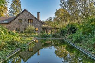 Deze villa, gelegen tussen de Leie en de Golf is ligt op een perceel van 5.089 m2 . Het perceel geniet van een zuidwestelijke oriëntatie, een eigen bos en een groot zwembad. De woning dateert van 1988 en heeft een bewoonbare oppervlakte van 528m2. Hierdoor biedt deze woning enorm veel potentieel.<br /><br />Het gelijkvloers is als volgt opgedeeld: inkomhal met gastentoilet, ruime bureauruimte, eventuele eerste slaapkamer. Grote, open leefruimte met veel lichtinval. Keuken met bijkeuken die toegang biedt tot de garage waar plaats is voor twee wagens en extra opbergruimte. Verder is er nog een praktische kelder.<br /><br />De eerste verdieping biedt plaats voor drie ruime slaapkamers en een badkamer. Daarnaast zorgt de grote polyvalente ruimte voor extra opportuniteiten.<br /><br />Naast de hoofdwoning is er tevens een bijwoning voorzien. U heeft toegang tot de bijwoning via een aparte inkomhal, maar ook via de garage en de polyvalente ruimte. De bijwoning heeft tevens een lift.<br /><br />Met al deze troeven biedt deze villa een uitzonderlijke woonervaring midden in de groene en exclusieve omgeving van Sint-Martens-Latem.