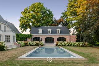 Deze karaktervolle Franse villa, ontworpen door architect Jules Delarue, onderging in 2021 een totaalrenovatie waarbij authenticiteit en hedendaags comfort harmonieus werden samengebracht. Een eigendom waar ruimte, licht en verfijnde materialen centraal staan.<br /><br />De woning biedt royale leefruimtes met een tijdloze uitstraling, gekenmerkt door onder meer marmeren vloeren, parket, sierlijsten en een sfeervolle haard. De leefkeuken werd uitgerust met hoogwaardige Miele toestellen en vormt samen met het verfijnde maatwerk een mooi geheel. <br /><br />De eerste verdieping omvat vier slaapkamers, drie badkamers en een ruime dressing. Daarnaast beschikt de woning over een volledig onderkelderde verdieping met tal van praktische ruimtes en een tweede bovenverdieping die polyvalent kan worden ingericht als bureau, speelruimte, extra slaapkamers of cinemaruimte.<br /><br />Ook buiten werd een bijzonder kwalitatief totaalconcept gerealiseerd. De aangelegde tuin met terrassen in oud marmer, het stijlvolle zwembad en het afzonderlijk toegankelijke poolhouse creëren een unieke woonbeleving. Het poolhouse, afgewerkt met eikenhout, natuursteen en vloerverwarming, leent zich perfect als kantoor, atelier of ontspanningsruimte.<br /><br />Een uitzonderlijke eigendom waar karaktervolle architectuur, hoogwaardige afwerking en een aangename connectie met de buitenomgeving samenkomen.