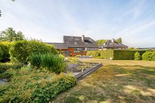 Cette maison surprend dès le premier instant. Derrière la façade discrète se cache une maison spacieuse, moderne et extrêmement pratique où le confort, la fonctionnalité et la qualité de vie sont au centre.<br /><br />En entrant, on remarque immédiatement l'excellente disposition. Au rez-de-chaussée, la maison dispose d'un double garage et d'un espace supplémentaire polyvalent actuellement utilisé comme salle d'exposition, mais pouvant être aménagé en espace de pratique, bureau ou espace de loisirs. Grâce à l'ascenseur, chaque étage est facilement accessible, ce qui rend cette maison particulièrement tournée vers l'avenir.<br /><br />Au rez-de-chaussée, vous trouverez également un sauna et une douche, donnant un accès direct au jardin. Le magnifique jardin arrière est un véritable oasis de verdure et de calme. Vous pourrez profiter d'un bel étang, d'une cabane de jardin pratique et d'une sortie arrière séparée, idéale pour l'entretien du jardin ou le transport de matériel sans devoir passer par la maison.<br /><br />En empruntant l'escalier ou l'ascenseur, vous accédez au premier étage où se trouve le spacieux espace de vie. De grandes fenêtres offrent une abondance de lumière naturelle et une vue magnifique sur le jardin verdoyant. À côté se trouve la cuisine semi-ouverte entièrement équipée, en parfaite harmonie avec le caractère ouvert et accueillant de la maison.<br /><br />La véritable attraction de cet étage est sans aucun doute la terrasse exceptionnellement spacieuse. Vous pourrez profiter de la vue sur le vert en toute intimité, tandis qu'une rampe pratique assure une connexion fluide et directe avec le jardin.<br /><br />Au deuxième étage se trouve la zone de nuit. La spacieuse chambre principale dispose de sa propre salle de bains et dressing, offrant une véritable sensation d'hôtel à la maison. Il y a également deux autres chambres à coucher complètes et une deuxième salle de douche qui complètent le confort pour la famille ou les invités.<br /><br />Le dernier étage est actuellement aménagé en espace de bureau, mais peut facilement être transformé en une chambre supplémentaire, un espace de loisirs ou un espace polyvalent selon vos souhaits.<br /><br />La cave offre également beaucoup d'espace. Vous y trouverez de nombreux espaces de rangement, une salle de sport entièrement équipée et une cave à vin chaleureuse. De plus, cet étage est également accessible par l'ascenseur, ce qui augmente encore la facilité d'utilisation.<br /><br />Enfin, cette maison bénéficie d'un excellent emplacement. L'accessibilité est particulièrement fluide, tandis que dans le jardin arrière, vous pourrez profiter pleinement du calme et de l'intimité, sans être dérangé par la route devant.