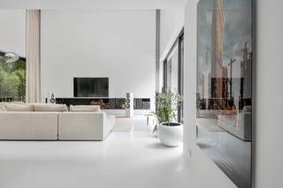 Op een prachtige locatie in Schilde bevindt zich deze unieke, moderne villa op een perceel van 3.848 m², omringd door natuur, rust en privacy.<br /><br />De woning werd ontworpen met oog voor esthetiek, comfort en duurzaamheid, en springt meteen in het oog dankzij haar moderne architectuur met warme gevelafwerking in hout. De voorgevel straalt ingetogen elegantie uit, waarbij ramen subtiel schuilgaan achter verticale houten latten, wat zorgt voor een strak en harmonieus geheel.<br /><br />Bij aankomst leidt een uitnodigend pad u naar de formele inkom van de woning, waar een hal met royale plafondhoogte en een elegante traphal u verwelkomt. Achter een ingewerkte kastenwand bevinden zich een gastentoilet en een vestiaire, beiden discreet en stijlvol geïntegreerd in het ontwerp. Deze inkomruimte zet meteen de toon voor wat volgt: een woning waarin ruimte, licht en functionaliteit centraal staan. De leefruimte vormt het kloppende hart van het huis en wordt gekenmerkt door grote raampartijen die de natuur als het ware naar binnen trekken. De zithoek is ruim en geniet van een indrukwekkende plafondhoogte. Een ingebouwde houthaard achter glas zorgt hier voor extra sfeer en warmte. Aansluitend bevindt zich de eetkamer, centraal gelegen tussen de zitruimte en de open keuken, en perfect voor gezellige diners. De keuken zelf is volledig uitgerust met hoogwaardige toestellen en werd stijlvol geïntegreerd in een strakke kastenwand en in het grote kookeiland. Achter de keuken bevindt zich een praktische berging met wasplaats.<br /><br />Via de leefruimte heeft u toegang tot de patio: een intieme, zuidgerichte buitenruimte met een ruim terras en een prachtig aangelegde zwemvijver. Deze afgesloten plek vormt een oase van rust en biedt volledige privacy, ideaal om te ontspannen of gasten te ontvangen in de zomer. De patio is uitsluitend toegankelijk via de leefruimtes, wat zorgt voor een unieke verbondenheid tussen het interieur en het exterieur, zonder afbreuk te doen aan de privacy van de woning zelf.<br /><br />Vooraan op het gelijkvloers bevindt zich een aparte kamer die perfect kan dienen als praktijkruimte, bureau of extra slaapkamer. Deze ruimte beschikt over een eigen badkamer met douche en lavabo, waardoor ze ook geschikt is voor gasten of voor professioneel gebruik. Daarnaast vinden we nog een fitnessruimte/bureelruimte terug op het gelijkvloers.<br /><br />Op de verdieping vinden we een zeer ruime bureauruimte die eenvoudig kan worden opgedeeld in twee volwaardige slaapkamers. De nachthal biedt toegang tot een apart nachttoilet. De master bedroom is een waar toevluchtsoord, voorzien van een ingemaakte dressing en een luxueuze en-suite badkamer. Deze badkamer beschikt over een inloopdouche, een ligbad, een dubbele lavabo met spiegelkast en een ingebouwde sauna, waardoor u elke dag kan genieten van wellness in eigen huis.<br /><br />De tuin rondom de woning is doordacht aangelegd in harmonie met de bosrijke omgeving. Het terrein is natuurlijk, met mooie graszones die overgaan in het omringende groen, en biedt een perfecte balans tussen openheid en beschutting. De aparte garage is volledig in dezelfde stijl opgetrokken als de woning, met plaats voor twee wagens en extra bergruimte.<br /><br />Deze woning is een uitzonderlijk aanbod voor wie houdt van moderne architectuur, natuurlijke materialen en rust, zonder in te boeten op comfort, luxe en functionaliteit. Een zeldzaam pareltje in het residentiële hart van Schilde.