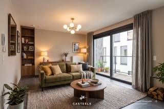 <br />Een nieuwbouwappartement geschikt voor jong en oud die rustig willen wonen in de Vlaamse Ardennen.<br /><br />Comfortabel en energiezuinig wonen in Kluisbergen. Dit nieuwbouwappartement heeft een gunstige ligging in het gebouw op de 1e verdieping. Hierdoor geniet u van extra lichtinval en een binnenpatio. Het appartement is reeds volledig afgewerkt; enkel de schilderwerken moeten nog worden uitgevoerd.<br /><br />De troeven van dit appartement:<br />-Unieke ligging: Met veel natuurlijke lichtinval en zicht op de binnenpatio.<br />-Energiezuinig &amp; toekomstbestendig: Dankzij de recentste isolatienormen en moderne bouwtechnieken geniet u van een uiterst lage energiefactuur en een aangenaam, constant binnenklimaat.<br />-Optimaal comfort: U geniet van het comfort van wonen op de 1e verdieping met een eigen, onderhoudsvriendelijk terras om in alle rust buiten te zitten.<br />-Volledig afgewerkt (incl. schilderwerken naar eigen smaak): Het appartement is helemaal instapklaar op de schilderwerken na. Deze zijn reeds inbegrepen in de prijs, waardoor u het kleuren- en  afwerkingspalet nog volledig naar eigen wens kunt kiezen.<br /><br />De lichtrijke leefruimte is voorzien van een prachtige tegelvloer en loopt naadloos over in de moderne, volledig geïnstalleerde open keuken. Daarnaast beschikt het appartement over één volwaardige slaapkamer, een berging en een ruime badkamer.<br /><br />Unieke gemeenschappelijke faciliteiten:<br />Naast uw privatieve terras heeft u direct toegang tot de grote, mooi aangelegde gemeenschappelijke tuin met een petanquebaan, een ontmoetingszaal voor bewoners, een infraroodcabine en een ruime, veilige fietsenberging.<br /><br />Uitstekende ligging &amp; bereikbaarheid<br />Het appartement is prachtig gelegen in het hart van de Vlaamse Ardennen, op een boogscheut van het Kluisbos en bekende wandel- en fietsroutes zoals de Oude Kwaremont.<br /><br />Ondanks de rustige en groene omgeving is de bereikbaarheid uitstekend:<br />-Verbindingen: Dankzij de nabijheid van de N60, N36 en N453 bereikt u vlot omliggende steden en gemeenten zoals Oudenaarde, Ronse, Avelgem, Maarkedal en Mont-de-l'Enclus. De snelweg E17 (oprit Waregem of Deerlijk) bevindt zich op slechts 15 tot 20 minuten rijden.<br />-Voorzieningen: Winkels voor de dagelijkse boodschappen (onder meer Delhaize, Spar en Carrefour Express), evenals lokale bakkers, slagers en apotheken bevinden zich in de directe nabijheid. Uitgebreider shoppen kan makkelijk in het nabijgelegen Oudenaarde of Ronse.<br />-Scholen: Verschillende basisscholen (zoals GBS De Start) en kinderopvangvoorzieningen liggen op wandel- of fietsafstand. Middelbare scholen in Ronse en Oudenaarde zijn eveneens vlot bereikbaar.<br /><br />Neem gerust contact met ons op voor meer informatie of om een bezoek in te plannen!<br />Stedenbouwkundige inlichtingen: in aanvraag.