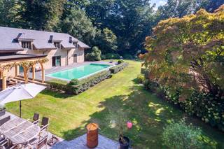 Deze riante villa heeft een zee van ruimte en een prachtig aangelegde parktuin met buiten zwembad en tennis, een echte familie-villa, een thuis! De villa heeft een uiterst gezellige leefkeuken met met prachtige open-haard. De keuken is zeer stijlvol en straalt vanwege de mooie duurzame materialen en luxe toestellen een zeer rustgevende sfeer uit. Via de schuifraam toegang naar het overdekte terras waar het zalig vertoeven is. Ook toegang naar de de riante tuin met uiterst veel privacy! Er is een zeer ruime living met grote open-haard, hier is er een grote raampartij waardoor binnen en buiten één geheel vormen. Er is een speels tv-kamer met open-haard en aanpalend een bureau ( dat afgesloten kan worden) met stijlvolle ingemaakte bibliotheek. Er is een grote eetkamer met authentieke stoof. De ruime gang breng ons naar de cosy bar. Ideale plek om vrienden te ontvangen. Er is ook een nog een afzonderlijke bureau-ruimte. De perfecte plek voor de kids om hun huiswerk te maken, vlakbij de keuken. De zij-inkom brengt ons naar de mudroom en de wellness ruimte met sauna, douche, kleedkamers, fitness. Hier directe toegang naar het zwembad en de tuin. De tuin met tennis is adembenemend en nodigt uit voor een wandelingetje. Op de verdieping zijn er 2 mooie slaapkamers met communicerende badkamer. De master bedroom met grote badkamer met ligbad, inloopdouche, toilet, pissin en dubbele lavabo. Er is een 4de en 5de grote slaapkamer. Een mooie badkamer met douche , ligbad en dubbele lavabo+toilet. Eer ruime wasplaats met extra spoelbak. Op de 2de verdieping is er een grote polyvalente ruimte die voor meerdere doeleinden kan dienen. Lift tot de 2 de verdieping. Er is een droge , functionele kelder + wijnkelder. Alarm, domotica, volledig omheind, automatische poort, bijhuis. Tennis met gravel. Buitenverlichting, beregeningsinstallatie, deze villa is voorzien van alle luxe. Parkeerplaats voor 6 wagens. Mogelijkheid tot carport. Kortom, deze villa is een riante villa met één sfeer, een thuis voor wie wil wonen in alle luxe en een oase van groen, een aanrader!!! Privacy alom! Epc B LABEL, AREI CONFORM, GEEN ASBEST.Voor meer info: www.domus-immobilien.be of bel Irene 0475/653581. Het is absoluut de moeite een bezoek ter plaatse te brengen!