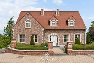 Voor meer info en foto’s, surf naar www.swevers.be – In de Groenstraat 42A in Glabbeek wacht deze uitstekend onderhouden villa uit 2003 op een nieuw gezin. Met een bewoonbare oppervlakte van 303 m² en een perceel van 22a 96ca biedt deze woning een zee aan ruimte en comfort. Doorheen de jaren werden diverse verbeteringen uitgevoerd, waaronder airconditioning, maatwerkkasten en een frisse schilderbeurt. De lichtrijke woonkamer van bijna 50 m² sluit aan op een gezellige veranda, terwijl de ruime keuken met kookeiland en praktische bijkeuken ideaal is voor het gezinsleven. Op het gelijkvloers bevinden zich verder een badkamer, bureau, gastentoilet, berging en een inpandige garage voor 2 à 3 wagens. De eerste verdieping telt drie ruime slaapkamers, een badkamer en twee dressings. De volledig afgewerkte zolder is ingericht als twee extra slaapkamers, waardoor de woning in totaal over vijf slaapkamers beschikt, maar kan ook perfect dienen als hobbyruimte of bureau. De volledige onderkeldering van 97 m² biedt tal van mogelijkheden voor opslag, werkplaats of hobbyruimte. Buiten geniet u van een verzorgde tuin met terrassen, petanquebaan en ruime grasvelden. Extra comfort wordt verzekerd door airconditioning, een alarmsysteem, elektrische garagepoorten en elektrische rolluiken. De rustige ligging combineert een vlotte bereikbaarheid met winkels, scholen, openbaar vervoer en de E40 en E314 in de nabije omgeving. Een instapklare en bijzonder complete villa waar ruimte, comfort en functionaliteit perfect samenkomen. Voor meer informatie, bel 011 255 155. Bron bewoonbare oppervlakte: EPC – verslag.