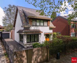 <p><strong>Stijlvolle open bebouwing in een rustige, groene omgeving nabij het centrum</strong><br /><br />In een rustige, boomrijke straat in een groene en gegeerde woonomgeving ontdekt u deze stijlvolle open bebouwing, waar rust, comfort en kwaliteit samenkomen. Scholen, winkels en openbaar vervoer bevinden zich op korte afstand, waardoor de ligging een ideale balans biedt tussen privacy en bereikbaarheid.</p>
<p>Zodra de automatische poort opent, wordt u meteen gecharmeerd door de woning en haar elegante, verzorgde uitstraling<strong>.</strong> De architecturale eenvoud, de harmonieuze inplanting en de verzorgde voortuin zetten onmiddellijk de toon voor wat volgt.</p>
<p>Binnen wordt u verwelkomd in een woning waar sfeer en verfijning centraal staan. Warme houten parketvloeren, subtiele gietijzeren accenten en zorgvuldig maatwerk creëren een tijdloze en elegante woonbeleving.</p>
<p>De leefruimte vormt het kloppend hart van de woning. Dankzij de grote raampartijen baadt de ruimte in natuurlijk licht en geniet u van een mooi zicht op de tuin. De open keuken sluit naadloos aan en versterkt het gevoel van ruimte, licht en verbondenheid.</p>
<p>De woning werd praktisch en doordacht ingedeeld met een inkomhal met gastentoilet en vestiaire, een ruime bijkeuken/wasplaats, een kelder en een ingemaakte bureauruimte die discreet in het geheel werd geïntegreerd.</p>
<p>Op de verdiepingen bevinden zich drie volwaardige slaapkamers, elk met hun eigen karakter. De master bedroom is uitgerust met airconditioning en beschikt over een royale badkamer met ligbad/douche en dubbele lavabo. De tweede slaapkamer geniet van een eigen douchekamer. De derde slaapkamer, gelegen op de bovenste verdieping en bereikbaar via een vaste trap, is volledig afgewerkt en voorzien van ingemaakte kasten die het geheel versterken.</p>
<p>Buiten wordt u omringd door groen en privacy. De aangelegde tuin met volwassen bomen vormt een serene buitenruimte waar u in alle rust kan ontspannen. Het perceel is volledig omheind en voorzien van een automatische poort en alarmsysteem, wat bijdraagt aan een veilig en comfortabel woongevoel.</p>
<p>Tot slot beschikt de woning over een losstaande garage met raampartijen, vandaag ingericht als fitnessruimte, waardoor ook hier flexibiliteit en multifunctionaliteit centraal staan.</p>
<p><strong>Troeven:</strong></p>
<ul>
<li>Instapklaar en hoogwaardig afgewerkt</li>
<li>Rustige, groene en gegeerde ligging</li>
<li>Lichtrijke leefruimte met open keuken</li>
<li>Twee badkamers</li>
<li>Aangelegde tuin met maximale privacy</li>
<li>Volledig omheind perceel met automatische poort</li>
<li>Alarmsysteem aanwezig</li>
<li>Kelder en praktische bergruimtes</li>
<li>Multifunctionele garage (momenteel fitnessruimte)</li>
</ul>
<p><br />Voor meer informatie of een bezichtiging aan deze gezellige woning, neem contact met Sigalit via sigalit@reds.be of op 0475668474</p>