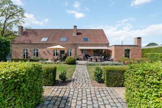 Deze indrukwekkende hoeve (bew opp.379.m²) met 4 slaapkamers, 2 badkamers, ruime leefkeuken, gezellige woonkamer, wasplaats, inpandige garage, polyvalente ruimte en ruim bijgebouw en tuinhuis is gelegen op een groen domein met prachtig uitzicht op omliggende weilanden. De woning biedt vele mogelijkheden. Hier geniet u van ruimte en rust op een interessante locatie in Herentals. <br /><br />Deze villa is volledig herbouwd in 2004 en biedt de mogelijkheid helemaal gelijkvloers te wonen of een apart woongedeelte te creëren voor een inwonend familielid. <br /><br />Indeling:<br />Gelijkvloers:<br />U betreedt de woning via de gezellige inkomhal met apart toilet en vestiaire. Via deze weg heeft u toegang tot de sfeervolle woonkamer op parket die een prachtig zicht heeft op het voorgelegen weiland. De open leefkeuken is voorzien van de nodige toestellen (kookvuur, oven, combi-oven, vaatwasmachine, koelkast en natuurstenen werkblad). Aansluitend aan de keuken bevindt zich de berging met ingemaakte kasten en vaatwasmachine. Op de gelijkvloerse verdieping is er ook een ruime slaapkamer aanwezig met bijhorende vernieuwde badkamer die voorzien is van douche en dubbele lavabo. Door een polyvalente ruimte (voorzien van houtkachel) kan dit stuk volledig apart als extra woongedeelte gebruikt worden of als atelierruimte voor de creatievelingen.<br /><br />Voorts is er ook een inpandige garage voorzien. <br /><br />Eerste verdieping:<br />De bovenverdieping is uitgerust met parket en is opgedeeld in een master bedroom met bijhorende dressing en 2 extra slaapkamers. De badkamer is ruim en voorzien van een ligbad, douche, lavabo en toilet. Praktische wasplaats en zeer ruime polyvalente ruimte die toegang geeft tot een extra zolder. <br /><br />Tuin:<br />In de tuin is het aangenaam vertoeven door de zuidoost oriëntatie en het weidse uitzicht aan de voorkant van de woning. Voorts bevindt er zich een tuinhuis met overdekt terras en een bijgebouw van +/- 80m² dat dienst kan doen als werkruimte (bespreekbaar om dit al dan niet aan te kopen).<br /><br />Bijzonderheden:<br />- Mogelijkheid extra stuk weiland aan te kopen<br />- Kwalitatieve afwerking<br />- 2 regenputten van 5.000l<br />- Bijgebouw dat dienst kan doen als werkruimte<br />- Mogelijkheid volledig gelijkvloers te wonen of extra aparte woonruimte te creëren