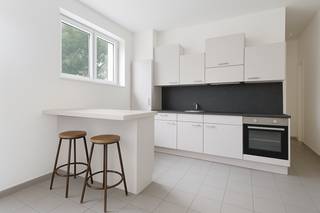 Appartement d'angle prêt à emménager avec terrasse ensoleillée sur le toit, idéalement situé près de l'UA. Idéal pour les primo-accédants ou les investisseurs<br />Cet appartement d'angle charmant se trouve dans cet immeuble bien entretenu, au calme, au premier étage.<br />La porte d'entrée sécurisée donne accès à un salon spacieux et lumineux (environ 40 m²), doté d'un sol carrelé facile d'entretien. La cuisine ouverte s'y intègre harmonieusement et est équipée d'une plaque à induction, d'un four, d'un évier et d'un réfrigérateur avec compartiment congélateur. Depuis le salon et la cuisine, vous profitez d'une vue dégagée sur l'agréable cour intérieure commune.<br />La chambre (environ 13 m²) offre un environnement calme pour dormir. La salle de bains récemment rénovée est élégamment finie dans un style mortex et équipée d'une baignoire avec fonction douche, d'un lavabo et de toilettes.<br />La terrasse commune sur le toit, d'une superficie de pas moins de 70 m², est un atout indéniable. C'est un endroit idéal pour se détendre au soleil et profiter de la vue sur l'église Saint-Antoine-de-Padoue toute proche. De plus, le bâtiment est équipé d'un ascenseur.<br />Cet appartement est une excellente opportunité pour ceux qui recherchent un logement prêt à emménager ou un investissement rentable. Chauffage central privé au gaz. Double vitrage.