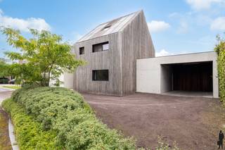<strong>Unieke architectenwoning gelegen in rustige, groene omgeving in één van de mooiste wijken te Olmen, nabij Meerhout en Leopoldsburg. De villa biedt o.a. 4 à 6 ruime slaapkamers, 2 badkamers, een uiterst lichtrijke, open leefruimte en een diepe, organisch ingerichte natuurtuin (met zonneterrassen en infinity-zwembad). Het geheel ligt op een perceel van ca. 2.101m², uitzonderlijk gelegen nabij natuur (wandel- en fietsroutes) en achtergelegen agrarisch gebied. De abstracte woning ademt klasse, karakter, visie en rust. De woning en tuin zijn opgebouwd op verschillende niveaus, wat zorgt voor een speelse, open dynamiek. Pure materialen zoals zichtbeton, en hardhout staan centraal. De enorme raampartijen halen de natuurlijke omgeving naar binnen en zorgen voor een fascinerende beleving van licht en ruimte. De villa is bovendien uiterst energiezuinig (zonnepanelen, vloerverwarming, etc.). Nabij scholen, openbaar vervoer en natuurreservaten (Keiheuvel & Nationaal Park Bosland). <br /><br /></strong><em>Gelijkvloers verdiep - eerste niveau</em><br /><br />Via de inkomhal met vestiairegedeelte en gastentoilet heeft u toegang tot de afzonderlijke praktijkruimte, de technische ruimte en waskamer. Het praktijkgedeelte is voorzien van wachtruimte. De hal leidt verder tot het privé-gedeelte (woonkamer, keuken, etc.). De leefruimte is verdeeld in een zitgedeelte (linkerzijde) met zwevende houtkachel, het eetgedeelte met achterliggende bureauruimte (centraal) en de open leefkeuken (rechterzijde). Deze leefruimte geniet van veel natuurlijk daglicht door de riante raampartijen die uitgeven op de diepe natuurtuin met verhoogd infinity-zwembad en vijverpartij. De keuken - met aansluitend ontbijtgedeelte - op hoogte is uitgerust met alle nodige kwaliteitstoestellen: inductievuur, heteluchtoven, Quooker, vaatwas, etc. (AEG, Faber, e.a.).<br /><br />Via deze leefkeuken heeft u toegang tot de bijkeuken met extra gootsteen en inbouwkastruimte, alsook tot de zij-ingang (carport).<br /><br /><em>Bovenverdiep - tweede en derde niveau</em><br /><br />Op de bovenverdieping zijn er 3 ruime slaapkamers en een badkamer. De hoofdslaapkamer is voorzien van een eigen ensuite-badkamer (nog onafgewerkt) en een inloopdressing. Deze slaapkamer biedt een prachtig uitzicht op de tuin. De badkamer is voorzien van inloopdouche en toilet. De ingerichte zolderverdieping doet thans dienst als 4e slaapkamer maar kan perfect worden opgedeeld of worden gebruikt als multifunctionele ruimte (bv. hobbykamer).<br /><br /><em>Buiten- en tuingebeuren</em><br /><br />De woning biedt vooraan buitenparking op lavasteenkorrel. Parkeren kan zowel voor de woning als onder de carport in zichtbeton (met berging). Zowel in de voor- als achtertuin bevinden zich groenstructuren (hoge hagen, heesters en diverse typen grassen). De achtertuin is volledig aangelegd en ideeal georiënteerd op het oosten. De uitgestrektheid van deze tuin en de verschillende private terrassen zorgen ervoor dat u in verschillende tuindelen in alle sereniteit van zon of schaduw kan genieten. De natuurtuin is verder volledig omheind en organisch aangelegd. U vindt er naast verschillende heggen, bomen, heester en een aantal fruit- en notenbomen ook een infinity-zwembad (verwarmd én jetstream / tegenstroomsysteem). <br /><br /><span>Bijzonderheden</span>:<br /><span>- EPC van 93kWh/m²/jaar: energielabel A<br /></span>- Conforme elektrische keuring én asbestveilig<br />- Hoogwaardige inrichting en structuren/materialen: vijver, zwembad<br />- Bewoonbare oppervlakte van maar liefst 347<span>m² (excl. kelder)</span><span><br /></span>- CV op aardgas en vloerverwarming<br />- Zonnepanelen en batterijklaar<br />- Riant perceel op oosten: 2.101<span>m²</span><br />- Renovatiejaar 2020-2024<br /><br />Neem alvast een kijkje via de virtuele toer: https://tour.giraffe360.com/6e228dfe55ab4722a71b85186a3cb399/