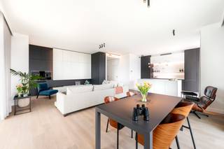 <p>Stijlvol appartement gelegen op het Eilandje, in het iconische Chipperfield-project, met spectaculair zicht. Gelegen op de 13e verdieping van een residentie met 15 verdiepingen, geniet u hier van een uitzonderlijk panoramisch uitzicht over de stad, de haven en het water.</p>
<p>Een brede, lichtrijke inkomhal biedt toegang tot alle kamers en leidt naadloos naar een ruime leefruimte. Een hoogwaardige Bulthaupt-keuken is voorzien van Miele-apparatuur, inclusief stoom- en grilloven. De leefruimte, met 3,2 meter hoge plafonds, is afgewerkt met een warme parketvloer en beschikt over ingemaakt kastenwerk met bar en een elegante ethanolhaard. Dankzij de kamerhoge raampartijen en meerdere glazen schuifpuien geniet u vanuit elke hoek van een adembenemend panorama over het Kattendijkdok en de Antwerpse skyline.</p>
<p>Vanuit alle kamers heeft u toegang tot het zuidgerichte omloop-hoekterras, één van de unieke troeven van dit appartement. Op deze hoogte geniet u ongestoord van het water, de stad en de haven — met een glazen balustrade die het zicht maximaal vrijlaat.</p>
<p>Verder beschikt het appartement over een master-slaapkamer met ensuite badkamer voorzien van inloopdouche, dubbele wastafel en toilet, afgewerkt in Corian. De oorspronkelijke tweede doucheruimte werd omgebouwd tot een praktische wasplaats (volledig ingericht, maar eenvoudig opnieuw als douchekamer te gebruiken). Daarnaast is er een tweede kamer ingericht als bureau met ingebouwde kasten en een geïntegreerd stapelbed, waardoor deze ook perfect kan functioneren als volwaardige tweede slaapkamer.<br /><br /><strong>De twee ondergrondse autostaanplaatsen kunnen aangekocht worden voor € 80.000; de kelderberging is inbegrepen.</strong></p>
<p>Een zeldzame kans om te wonen op één van de meest exclusieve locaties van Antwerpen, hoog boven de stad, in één van de meest gegeerde en dynamische buurten waar erfgoed en hedendaagse architectuur elkaar ontmoeten. Op wandelafstand van het MAS, sfeervolle terrassen aan het water, toprestaurants, boetieks en uitstekende verbindingen met de rest van de stad.</p>