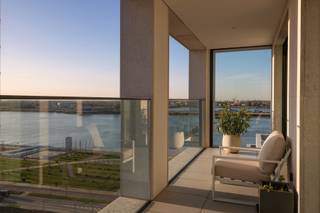 Welkom in een eigentijdse woonbeleving waar licht, ruimte en panorama centraal staan. Dit exclusieve appartement op de negende verdieping (2024) combineert modern comfort met een adembenemend uitzicht over de stad en de Schelde.

De leefruimte straalt openheid en rust uit, met een warme bamboeparketvloer en grote raampartijen langs drie gevels die zorgen voor uitzonderlijk veel natuurlijk licht. Het frontale zicht op de Schelde en het panoramische stadsbeeld maken elke dag bijzonder.

De volledig uitgeruste keuken verenigt functionaliteit en esthetiek en wordt aangevuld met een ruime bijkeuken. Aansluitend zijn er een noord- en zuidgericht terras en een winterterras, zodat u het hele jaar door van het buitengevoel geniet.

Het appartement telt twee slaapkamers: een master bedroom met ensuite badkamer en dressing, en een tweede kamer met douchekamer, ideaal als logeer- of bureauruimte. Een apart gastentoilet vervolledigt het geheel.

Twee inpandige parkeerplaatsen zijn beschikbaar aan €45.000 per stuk, exclusief btw. De aankoopprijs is eveneens exclusief btw.

Een lichtrijk en luxueus appartement in het hart van Antwerpen.