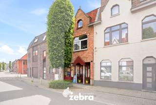 Deze eigendom geniet van een uitstekende ligging in een aangename en residentiële buurt van Brugge. Dankzij de centrale locatie bevinden winkels, scholen, horeca en diverse diensten zich op korte afstand. Ook het openbaar vervoer is vlot bereikbaar, waardoor u zich gemakkelijk binnen Brugge en de ruime regio kunt verplaatsen.<br /><br />Deze gesloten bebouwing betreedt u via de handelsruimte, die momenteel ingericht is als winkel. Aansluitend vindt u de keuken met gezellige zit- en eetruimte.<br />Het gelijkvloers beschikt verder over een badkamer en een ruime berging. Achteraan bevindt zich een ruime garage met zolderruimte.<br />Via de hal heeft u toegang tot de droge kelder.<br /><br />De eerste en tweede verdieping bieden samen vier volwaardige, lichtrijke slaapkamers. Op de tweede verdieping is bovendien een extra toilet aanwezig.<br />Via een uitschuifbare zoldertrap bereikt u de bergzolder.<br /><br />Verder beschikt de woning over zonnepanelen met omvormer en thuisbatterij, een condenserende gasketel en conforme elektriciteit.<br /><br />Kortom, een unieke opportuniteit voor zelfstandigen, ondernemers of gezinnen die op zoek zijn naar ruimte, comfort en energiezuinigheid.<br /><br /><strong>Ook wild geworden van deze thuis?<br />Twijfel niet langer en leg vandaag nog uw bezoek vast!</strong>