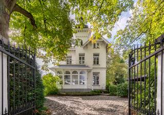 <h1><span>Karaktervolle villa met torentje en ruime tuin in Kapellen</span></h1>
<p><span>In de Eikendreef in Kapellen bevindt zich deze karaktervolle woning uit 1880. De villa ligt in een rustige, groene omgeving en onderscheidt zich door haar typische architectuur, met een torentje, geschilderde bakstenen gevels en karakteristieke dakpartijen.</span></p>
<p><span>De woning werd opgetrokken in cottagestijl, een bouwstijl die herkenbaar is aan de combinatie van verschillende dakvormen en decoratieve details. Het torentje geeft de woning een eigen uitstraling. Ook de gevels en de overige architecturale elementen verwijzen naar de bouwstijl van die periode.</span></p>
<p><span>Binnen beschikt de woning over vijf slaapkamers en twee badkamers. De verschillende ruimtes bieden mogelijkheden voor een gezin dat op zoek is naar een woning met karakter en voldoende plaats. Afhankelijk van de wensen van de toekomstige eigenaar kan de indeling verder worden aangepast. De woning is opgenomen als bouwkundig erfgoed. Afhankelijk van het toepasselijke erfgoedstatuut en de wettelijke voorwaarden kan een vrijstelling van de Vlaamse renovatieverplichting gelden.</span></p>
<p><span>De woning beschikt over een ruime tuin die volop mogelijkheden biedt om buiten te genieten. De groene omgeving en de rustige ligging maken dit tot een aangename plek om te wonen.</span></p>
<p><span>Achteraan op het perceel bevindt zich bovendien een afzonderlijke conciërgewoning van ca. 120 m², met een ruime garage. Het gebouw dient te worden gerenoveerd, maar biedt verschillende mogelijkheden, zoals een kangoeroewoning, gastenverblijf, kantoor of praktijkruimte.</span></p>
<p><span>Een woning met een eigen bouwkundige uitstraling, een ruime tuin en een bijkomend gebouw dat mogelijkheden biedt voor wie op zoek is naar extra ruimte.</span></p>