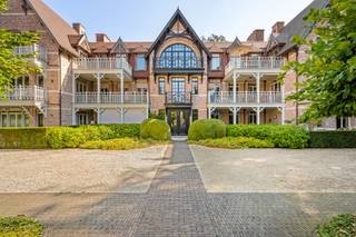 Uitzonderlijk villa-appartement van ca. 330 m²! <br />Een zeldzame combinatie van de ruimte en grandeur van een royale villa met het comfort, de privacy en het onderhoudsgemak van residentieel wonen. De statige architectuur, fraai aangelegde tuinen en hoogwaardige afwerking onderstrepen het exclusieve karakter van het geheel. Met zijn uitzonderlijke woonoppervlakte, royale buitenruimtes en bijzonder doordachte indeling, is dit appartement het absolute topsegment van Schilde.<br /><br />Indeling:<br />De privatieve inkomhal met vestiaire en toilet, vormt meteen een stijlvolle introductie en geeft via elegante stalen binnendeuren toegang tot de leefruimtes.<br /><br />Centraal bevindt zich de uitzonderlijk royale woonkamer van ca. 90 m², opgedeeld in verschillende harmonieus verbonden leefzones met een formele eetkamer, ruim salon rond de gashaard en bijkomende zit- en leeshoeken. Hoogwaardig maatwerk, warme parketvloeren en talrijke raampartijen zorgen voor een tijdloze en verfijnde sfeer.<br /><br />De ruime leefkeuken van ca. 38 m² vormt een tweede volwaardige leefruimte en werd uitgerust met een groot centraal eiland, natuurstenen werkbladen, uitgebreid maatwerk en hoogwaardige Miele-toestellen. De geïntegreerde eetplaats, eveneens met gashaard, sluit rechtstreeks aan op het grotendeels overdekte terras van ca. 26,9 m². Een praktische bijkeuken/berging vervolledigt deze zone.<br /><br />De master suite vormt een bijzonder private vleugel met een royale slaapkamer van ca. 37 m², een volledig op maat ingerichte dressing van ca. 18 m² en een luxueuze badkamer met dubbele wastafel, inloopdouche en lig-/whirlpoolbad. De slaapkamer geeft rechtstreeks toegang tot de buitenruimtes aan de achterzijde.<br /><br />Een 2e ruime slaapkamer beschikt over maatwerk, een eigen balkon en een afzonderlijke badkamer met inloopdouche. Het aparte bureau van ca. 25,5 m² aansluitend aan de woonkamer, kan dankzij zijn royale afmetingen perfect opnieuw als 3e slaapkamer worden ingericht.<br /><br />Verspreid over verschillende zijden beschikt het appartement over vijf terrassen en balkons, samen goed voor ca. 62 m² buitenruimte. Vooraan geniet men van een ruime en beschutte buitenkamer aansluitend aan de leefkeuken, terwijl de terrassen achteraan uitkijken over het volwassen groen van het domein.<br /><br />Bijzonderheden:<br />- Ca. 330 m² bewoonbare oppervlakte<br />- Uitzonderlijk royale leefruimte van ca. 90 m²<br />- Leefkeuken van ca. 38 m² met Miele-toestellen<br />- 2 slaapkamers + bureau / mogelijkheid tot 3 slaapkamers<br />- 2 badkamers<br />- Master suite met ruime dressing<br />- Ca. 62 m² terrassen en balkons<br />- Afgesloten garagebox voor 2 grote wagens met extra bergruimte<br />- Afzonderlijke privatieve kelderberging<br />- Hoogwaardig maatwerk en tijdloze afwerking<br />- EPC-label A