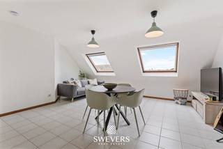 Voor meer info en foto’s, surf naar www.swevers.be – Op de derde verdieping van een verzorgd gebouw aan de Vredelaan 43 bus 3.01 in Houthalen-Helchteren ligt dit praktisch ingedeelde 1-slaapkamerappartement. Het gebouw dateert van 1988 en heeft een bewoonbare oppervlakte van 65m2. Dankzij de centrale ligging bevinden winkels en openbaar vervoer zich op amper 50 meter. Ook scholen, ontspanning, restaurants en belangrijke verbindingswegen zijn vlot bereikbaar. Ideaal voor eigen bewoning of als investering met het oog op verhuur. Het appartement beschikt over een lichtrijke leefruimte van 26,88 m² met grote raampartijen en dakramen. De open keuken van 4,70 m² sluit hier rechtstreeks op aan en werd in 2019 vernieuwd. Er is voldoende ruimte voor een gezellige zit- en eethoek. De ruime slaapkamer van 16,40 m² biedt plaats aan een dubbel bed en extra kastruimte. De badkamer is uitgerust met een douche, wastafelmeubel en toilet. Het badkamermeubel en toilet werden in 2019 vernieuwd en in 2024 kwam er een nieuwe spiegelkast bij. Doorheen de jaren werd het appartement gericht opgefrist. Zo werd in 2008 het Velux-dakraam in de badkamer vernieuwd en voorzien van een PVC-afwerking en dubbele beglazing en werden in 2019 onder meer de keuken en boiler vernieuwd. De elektriciteit is conform. Er is geen terras, maar de natuurlijke lichtinval, onderhoudsvriendelijke indeling en centrale ligging vormen duidelijke troeven. Een interessant appartement voor wie comfortabel en centraal wil wonen of op zoek is naar een vlot verhuurbare investering in Houthalen-Helchteren. Voor meer informatie, bel 011 255 155. Bron bewoonbare oppervlakte: EPC – verslag.