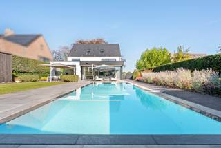 Op korte afstand van het centrum van Hoogstraten bevindt zich deze verrassend ruime BEN-villa op een zuidgericht perceel van 1.320 m². De woning werd in 2019 quasi volledig nieuw heropgebouwd en haalde bijgevolg een E-peil 3 ! De villa biedt vandaag ca. 433 m² aan woonoppervlakte, waarbij ruimte, licht en hedendaags wooncomfort centraal staan. De grote raampartijen creëren een sterke verbinding tussen binnen en buiten en laten de leefruimtes volop genieten van het zicht op de tuin. Het verwarmde zwembad en het volwaardig ingerichte poolhouse versterken het gevoel van wonen en ontspannen in eigen huis.<br /><br />De villa is opgebouwd rond een royale, open leefruimte waar zithoek, eetplaats en keuken op een natuurlijke manier met elkaar verbonden zijn. Het salon met gashaard vormt een gezellige zithoek, terwijl de ruime open keuken met centraal eiland en ontbijtgedeelte uitnodigt tot een gezellig samenleven. De keuken is voorzien van alle modern comfort met oa stoomoven, combi-oven, inductiekookplaat met inbouwafzuiging, wijnkoeler,.. <br />Een afzonderlijk bureau en een bijkomende polyvalente kamer bieden ruimte voor thuiswerk, hobby's of een speelkamer. Praktisch comfort is er dankzij de aansluitende wasplaats, berging, technische ruimte en kelder.<br />Een strakke trap in mooi staal brengt u naar de bovenverdieping. Hier bevindt zich de masterbedroom met afzonderlijke dressing en eigen badkamer voorzien van vrijstaand ligbad, ruime inloopdouche en dubbele lavabo. Verder twee ruime slaapkamers met inbouwkasten en een tweede badkamer met dubbele lavabo en douche. De volledig afgewerkte tweede verdieping biedt nog een grote hobbykamer/polyvalente kamer, dewelke ook dienst kan doen als 4de slaapkamer. Verder nog een bijkomende berg- en technische ruimte. <br /><br />Ook buiten werd veel aandacht besteed aan ruimte en privacy. De zuidgerichte, volledig omheinde tuin vormt een aangename verlenging van de leefruimtes en werd ingericht met verschillende terrassen rondom het verwarmde zwembad. Hier is volop ruimte voor lange zomerdagen, een loungehoek of gezellig tafelen met familie en vrienden, terwijl achteraan nog voldoende gazon en speelruimte behouden blijft.<br />Het vrijstaande poolhouse maakt het buitenleven compleet en functioneert als een volwaardige extra leefruimte. Met een eigen keuken (voorzien van vaatwasser, oven, koelkast met diepvriezer), een douche en toilet leent het zich perfect als lounge, fitness- of ontspanningsruimte en vormt het tegelijk een ideale plek om gasten te ontvangen.<br /><br />Ook aan het praktische aspect werd gedacht. Zowel voor als naast de woning is ruime parkeergelegenheid voorzien, inclusief laadinfrastructuur voor elektrische wagens. <br /><br />Bijzonderheden: <br />- Sterke technische en energetische uitrusting. Met een E-peil van slechts 3 betreft het bovendien een uiterst energiezuinige BEN-woning.<br />- een geothermische warmtepomp met vloerverwarming en passieve koeling<br />- zonnepanelen van 11 kW<br />- ventilatiesysteem type D<br />- domotica<br />- alarmsysteem, buitendetectie, automatische toegangspoort, rookdetectoren<br />- regenwaterput van 14.000 liter, aangesloten op toiletten en buitenkraan<br />- screen aan de leefkeuken en oversteek - rolluiken op de eerste verdieping<br />- een verwarmd zwembad met automatisch rolluik <br />- laadinfrastructuur voor elektrische wagens aanwezig. <br />- een opportuniteit voor wie wil wonen in een compleet instapklare villa met groot volume aan woonruimte, energiezuinigheid, privacy en een uitgesproken binnen-buitenbeleving.