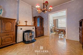 Voor meer info en foto’s, surf naar www.swevers.be – Op zoek naar een woning met karakter en renovatiemogelijkheden? Aan de Heerbaan 145 in Koersel bevindt zich deze halfopen bebouwing uit 1938 met 139 m² bewoonbare oppervlakte, twee ruime slaapkamers en een perceel van maar liefst 860 m². Op het gelijkvloers vind je een inkomhal, een gezellige zitkamer van 16,80 m², een eetkamer en een aparte keuken van 16,80 m². De veranda biedt uitzicht op de tuin en kan na renovatie een aangename ontspanningsruimte worden. Verder zijn er een wasruimte, afzonderlijk toilet en een ruime aangebouwde garage van 33 m². De eerste verdieping telt twee volwaardige slaapkamers van elk 16,80 m² en een badkamer die in 2021 werd vernieuwd. Extra opbergruimte is beschikbaar in de kelder van 10,50 m² en op de ruime zolder van circa 48 m² grondoppervlakte. Het noordwestelijk georiënteerde perceel van 860 m² biedt volop mogelijkheden voor een terras, speelruimte of moestuin. De woning beschikt over rolluiken, ramen uit 2004 en verwarming op mazout. De ligging is praktisch, met openbaar vervoer op 300 meter, scholen op 750 meter en winkels op circa 2 kilometer. De snelwegen bereik je op ongeveer 5,2 kilometer. Deze te renoveren woning vormt de ideale basis voor wie een thuis volledig naar eigen smaak wil creëren. Voor meer informatie, bel 011 255 155. Bron bewoonbare oppervlakte: EPC – verslag.