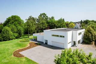 <br />Moderne luxe-villa met heel mooie tuin bestaande uit een inkomhal, living, ingerichte ruime keuken, bijkeuken, 2 slaapkamers, 2 badkamers, dressing, strijkkamer, wasplaats, dubbele garage en berging.<br />Op verdiep een appartement met aparte ingang en een living met open keuken, 3 slaapkamers, 3 badkamers, dressing en een terras.<br />Overdekt terras, zwembad en poolhouse op 5.664m². Ideaal voor kangoeroewonen. Ca. 600m² vloeroppervlakte. <br />