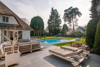 Op een zeer gegeerde en residentiële locatie in Essen-Heikant treffen we deze karaktervolle luxevilla, die in 2015 een renovatie onderging met duurzame en hoogwaardige afwerkingsmaterialen, en die zich in een perfecte staat van onderhoud bevindt.<br /><br />De entree geeft uit op de royale leefruimte op parketvloer. De living is ingedeeld in een gezellige zithoek en een eetkamer. Een sfeervolle gashaard vormt hierbij een centraal element tussen beide ruimtes.<br /><br />De leefkeuken is ingericht met alle hedendaagse apparatuur en beschikt tevens over een eetkamer.<br />Aansluitend op de keuken treffen we een bijkeuken en een kelder met aansluitingen voor de wasmachine en de droogkast. <br />Van hieruit is er toegang tot de dubbele garage met automatische toegangspoorten en een trap die (met traplift) leidt tot de fitnessruimte op de eerste verdieping. <br /><br />Links van de inkomhal komen we in een kantoor (eventueel gelijkvloers slaapkamer) met aansluitende badkamer die is voorzien van een ligbad, inloopdouche, dubbele lavabo en een toilet. <br /><br />Op de eerste verdieping geeft de zeer ruime overloop uit op de hoofdslaapkamer met dressing. <br />Verder zijn er nog drie ruime slaapkamers en een panic room. <br />De badkamer is ingericht met een douche en een enkele lavabo. <br />Ten slotte vinden we nog een apart nachttoilet.<br /><br />De woning is gebouwd op een ruim en lichtrijk perceel van ca. 2.643 m².<br />De zonnige tuin werd met de grootste zorg aangelegd met een vernieuwd terras (2022), een verwarmd zwembad met lounge en buitendouche en een koivijver.<br /><br />Algemeen:<br /><br />• Renovatie in 2015 met nieuwe keuken, vloeren, deuren,… met behulp van een binnenhuisarchitect.<br />• Het dak werd vernieuwd in 2025.<br />• Het terras werd vernieuwd in 2022.<br />• Beveiliging: Kogelvrij glas, 6 inbraakveilige deuren, alarminstallatie verbonden met de meldkamer en voorzien van een stil alarm.<br />• CV op stookolie met nieuwe ketel in 2021.<br />• Overal rolluiken.<br /><br />Deze villa is gelegen aan de Elzendreef, een zeer residentiële en rustige buurt in Essen-Heikant.<br />Er is een vlotte bereikbaarheid naar Antwerpen, Brussel en Nederland, zowel met de wagen als vanuit het treinstation van Essen.