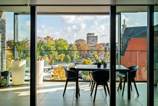 Sale under registration fees. This ready-to-move-in and spacious apartment is located on the Kolonel Dusartplein, on the inside of the small ring of Hasselt. When you step outside, you are right in the bustling center of Hasselt. There are 2 spacious terraces of 21m² and 14m² with a beautiful view over the square.<br /><br />Layout:<br />The apartment is accessible via stairs and an elevator, with only 2 apartments per floor using the elevator. Through the security door, we enter the entrance hall of the apartment. From here, we continue to the 78m² living room with open kitchen. In the living room, a custom-made desk has been created. What immediately catches the eye is the sea of light created by the floor-to-ceiling windows. The high-quality materials, such as the parquet floor, give the whole a luxurious look. There is a water vapor fireplace connected to the water supply and integrated into the TV/audio furniture. The open kitchen is fully equipped. The spacious terraces are well-oriented and also have lighting. Through the night hall, we have access to the master bedroom with ensuite dressing. There are also 2 spacious bedrooms. In the middle lies the beautiful and practical bathroom. The apartment is also equipped with several custom-made storage cabinets, making it extremely practical. There are 2 toilets, namely the guest toilet and another one in the bathroom. The spacious laundry room is provided in the technical storage room.<br /><br />In the basement, there is a spacious and easily accessible parking space (to be purchased) and a spacious cellar storage room. If desired, there is an additional parking space to be purchased. The parking is easily accessible via the small ring or via the Koning Boudewijnlaan. It concerns a part of the Q-parking which is only accessible to residents of the residence. In the basement, there is also a communal bicycle storage and container room.<br /><br />Extraordinary features:<br />- Very good location<br />- Ready to move in<br />- Beautiful view<br />- 143m² usable area (source EPC)<br />- 3 bedrooms<br />- 2 terraces<br />- Apartment with a spacious feel<br />- Energy efficient EPC A<br />- Cellar storage included<br />- Additional parking spaces to be purchased<br />- 2 entrance doors as 2 apartments have been merged.