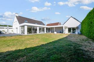 <strong>MODERNE BIJZONDERE ALLEENSTAANDE VILLA MET PRAKTIJKRUIMTE </strong><br />Een parel van hedendaagse architectuur waar luxe, licht en functionaliteit harmonieus samenkomen. Deze indrukwekkende villa combineert een bijzonder elegante uitstraling met een uitzonderlijke woonbeleving en biedt bovendien tal van mogelijkheden voor een zelfstandige praktijk, kantoor of zelfs een tweewoonst.<br />Achter een strakke elek.bediende grote poort komt u op een klein binnenplein met carr port en de inkom van de villa <br />Via de inkomhal betreedt u de bijzonder zeer ruime leefruimte met strakke moderne gashaard , waar grote raampartijen zorgen voor een overvloed aan natuurlijk licht en een voortdurende verbinding met de tuin. <br />De luxueus ingerichte designkeuken sluit naadloos aan bij het geheel en vormt samen met de aangrenzende open ruimte een bijzonder veelzijdige leefomgeving. Deze extra ruimte kan naar wens worden ingericht als aparte eetkamer, bureelhoek, speelruimte, hobbykamer. Voor pure ontspanning beschikt de villa over een heerlijke wellnessruimte met jacuzzi, aansluitend op een moderne douche. Daarnaast zijn er een praktische berging en een ruime dubbele garage.<br /><br /><strong>Praktijk of kantoor met eigen ingang</strong><br />Een absolute troef is de ruime praktijk-/kantoorruimte met volledig afzonderlijke toegang. Hierdoor kunnen klanten, patiënten of zakenrelaties ontvangen worden zonder de privésfeer te verstoren. De praktijk beschikt over een ruime wachtzaal (eventueel slaapkamer )aparte w.c. en een grote praktijkruimte met prachtig zicht op de tuin. Dankzij de indeling en de aparte ingang is deze vleugel bijzonder geschikt voor een vrij beroep, kantoor, praktijk aan huis of — mits de nodige vergunningen — als zelfstandige woonunit/tweewoonst<br /><br /><strong>Buitenleven op zijn best</strong><br />Ook buiten blijft deze villa verrassen. In de tuin die 100 % privacy heeft bevindt zich een moderne tuinkamer met keukenhoek , ideaal als lounge, hobbyruimte of stijlvolle ontvangstruimte. Het grote terras vormt de perfecte plek om in alle rust te genieten.<br /><br /><strong>Eerste verdieping</strong><br />Op de eerste verdieping bevinden zich vier slaapkamers, waarvan momenteel één kamer werd ingericht als ruime dressing. Daarnaast beschikt de verdieping over een ruime badkamer. Deze bijzondere villa is veel meer dan een ruime gezinswoning. Het is een stijlvol totaalconcept voor wie wonen en werken wil combineren, met bovendien de flexibiliteit om verschillende generaties, een zelfstandige professional of twee gezinnen comfortabel onder één dak te laten wonen.<br />Een uitzonderlijk pand met een uitgesproken moderne uitstraling, royale ruimtes, overvloedig licht, een tuin met veel privacy én een praktijkgedeelte met eindeloze mogelijkheden. Een villa die indruk nalaat<br /><strong>Extra s</strong><br />Dub garage + carport <br />Zonnepanelen met thuisbatterij<br />Airco’s<br />EPC 89 !<br />
