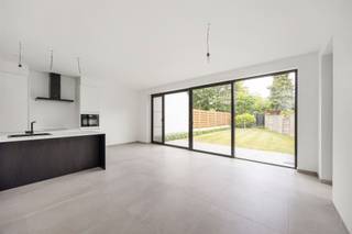 <p><span>Energiezuinig gelijkvloers appartement met terras en gemeenschappelijke tuin </span></p><p><span>Welkom in dit energiezuinige gelijkvloerse appartement, gelegen in een recent gebouwd appartementsgebouw aan de Schuurveldlaan. Hier geniet u van modern wooncomfort, een uitstekende label A en een aangename combinatie van binnen- en buitenruimte. Dankzij de energiezuinige technieken zoals de vloerverwarming, ventilatiesysteem type C+ én de aanwezige zonnepanelen, woont u hier niet alleen comfortabel maar ook bijzonder energie-efficiënt en toekomstgericht.</span></p><h2><span>Ligging</span></h2><p><span>Dit appartement heeft een zeer gunstige en strategische ligging aan de Schuurveldlaan, in de nabijheid van zowel het dorpscentrum van Wilrijk als Aartselaar. Daarnaast geniet u van een uitstekende verbinding naar de belangrijkste invalswegen richting Antwerpen en Brussel, wat deze locatie bijzonder interessant maakt voor pendelaars. U woont hier in een rustige woonomgeving met toch alle voorzieningen zoals winkels, scholen, horeca en openbaar vervoer binnen handbereik.</span></p><h2><span>Indeling</span></h2><p><span>Via de inkomhal, afgewerkt met een stijlvolle grijze tegelvloer, komt u meteen in een lichtrijke en aangename sfeer terecht. De inkomhal geeft toegang tot de verschillende ruimtes en leidt u verder naar de ruime leefruimte met open eilandkeuken.</span></p><p><span>De leefruimte geniet van uitzonderlijk veel natuurlijk licht dankzij de hoogrendements aluminium raampartijen over de volledige breedte. Deze bieden bovendien een mooi zicht op het privatieve terras en de gemeenschappelijke tuin. Twee ramen zijn voorzien van vliegenramen voor extra comfort. Via de schuifdeur bereikt u het privatieve terras van ca. 14 m², waar het heerlijk vertoeven is. De aanpalende gemeenschappelijke tuin voelt dankzij de beschutting quasi privatief aan en biedt een rustige groene omgeving om te ontspannen of gasten te ontvangen.</span></p><p><span>De open eilandkeuken is modern en hoogwaardig afgewerkt met onder meer een composiet werkblad en beschikt over alle hedendaagse toestellen: vaatwasser, oven, inductiekookplaat, koelkast, diepvries en voldoende kastruimte. Aansluitend bevindt zich een praktische berging met extra stockageruimte.</span></p><p><span>Verder bevindt zich links van de inkomhal de ruime slaapkamer, met voldoende plaats voor een dubbel bed en kastruimte. De badkamer is modern afgewerkt en voorzien van een inloopdouche, lavabo en handdoekradiator. Daarnaast is er nog een aparte technische ruimte met aansluiting voor wasmachine en droogkast.</span></p><p><span>In de ondergrondse verdieping beschikt u over een zeer ruime kelderberging, bereikbaar via lift of trap. Tevens is er een gemeenschappelijke fietsenberging aanwezig. De ondergrondse autostaanplaats dient verplicht mee aangekocht te worden voor een vraagprijs van 30.000 euro</span></p><p><span>Een extra troef is dat de aankoop kan gebeuren onder registratierechten (2%) in plaats van btw, wat financieel zeer interessant is.</span></p><h2><span>Troeven</span></h2><ul><li><span>Energiezuinig appartement met label A </span></li><li><span>Zonnepanelen aanwezig </span></li><li><span>Vloerverwarming </span></li><li><span>Ventilatiesysteem type C+ </span></li><li><span>Recent bouwjaar </span></li><li><span>Privatief terras en gemeenschappelijke tuin met quasi privatief gevoel </span></li><li><span>Zeer ruime kelderberging </span></li><li><span>2 privatieve plaatsen voor fietsen inbegrepen</span></li></ul><p><span> </span></p><p><span>Dit appartement combineert comfort, luxe en een uitzonderlijk buitengevoel op een toplocatie in Wilrijk.</span></p><p><span> </span></p>