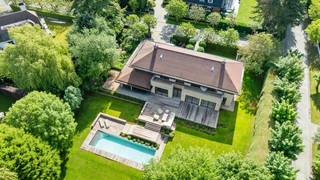 Gelegen in een uiterst rustige laan in het prestigieuze Domein van Bouchout te Wemmel, biedt deze groots opgezette villa hypermodern wooncomfort waar licht en ruimte centraal staan. De strategische ligging garandeert een serene, veilige leefomgeving nabij scholen, invalswegen en de Brusselse Ring.De indrukwekkende inkomhal leidt naar een royaal salon met design-gashaard en plafondhoge ramen, grenzend aan een formele eetkamer. De exclusieve eiken leefkeuken met granieten werkblad is voorzien van een centraal kookeiland, massief houten ontbijtbar en premium inbouwapparatuur (o.a. een rvs Amerikaanse koelkast en stoomoven). Grote schuiframen bieden toegang tot het terras. Aansluitend bevindt zich een praktische wasplaats/bijkeuken die doorsteekt naar de dubbele inpandige garage.Op de eerste verdieping biedt de nachthal toegang tot vier royale slaapkamers. De master suite beschikt over een maatwerk dressing en een luxe badkamer in travertijn natuursteen met ligbad. De overige drie slaapkamers zijn uitgerust met inbouwkasten en worden geflankeerd door twee moderne douchekamers. Een grote, geïsoleerde zolder biedt extra uitbreidingsmogelijkheden.De volledig omsloten loungetuin biedt 100% privacy dankzij de hagen. Centraal ligt het grote, verwarmde buitenzwembad (warmtepomp), omringd door een hardhouten terras en diverse zithoeken. Het perfect georiënteerde terras achteraan biedt een prachtig panorama over het volledige domein.Droomt u ook al weg? Neem dan snel contact op!Bestuursmaatregelen in het maatregelenregister: nee