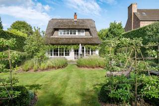 <p>Op een gegeerde locatie in De Sterre te Kapellen bevindt zich deze bijzonder charmante woning met rieten dak, een warme uitstraling en een verzorgde afwerking.</p>
<p>Via de inkomhal met vestiairekast komt u in de open leefruimte op eiken parket, waar de open haard meteen voor sfeer zorgt. Grote raampartijen brengen veel natuurlijk licht binnen en zorgen voor een aangename verbinding met de tuin. Aansluitend bevindt zich de open keuken, eveneens afgewerkt in eik en voorzien van een natuurstenen werkblad en AGA-fornuis. Vanuit de leefruimte en keuken is er rechtstreekse toegang tot het terras en de mooi aangelegde tuin.</p>
<p>Verder beschikt de woning over een praktische wasberging, een afzonderlijk toilet met handenwasser en een kelder.</p>
<p>Op de eerste verdieping geeft de ruime overloop op parket toegang tot twee volwaardige slaapkamers, voorzien van op maat gemaakte ingebouwde eiken kasten. Daarnaast is er een derde kamer die perfect dienst kan doen als slaapkamer, bureau of hobbyruimte.</p>
<p>De badkamer is uitgerust met een dubbele lavabo, een ruime inloopdouche en toilet. Daarnaast is er een zolder aanwezig die extra bergruimte biedt.</p>
<p>Een absolute troef is het volledig ingerichte bijgebouw achteraan in de tuin. Deze voormalige garage werd omgevormd tot een volwaardige multifunctionele ruimte en beschikt over veel natuurlijk licht, een pelletkachel en een mezzanine. Ideaal als bureau, atelier, hobbyruimte of extra verblijfsruimte.</p>
<p>De woning beschikt volgens het EPC over een bruikbare vloeroppervlakte van 138 m². Daarnaast biedt het ingerichte bijgebouw circa 28 m² extra gebruiksruimte. De kelder en zolder zijn niet inbegrepen in deze opgegeven oppervlaktes. Door de specifieke EPC-meetmethode wordt op de eerste verdieping bovendien enkel de oppervlakte vanaf 1,50 m vrije hoogte meegerekend.</p>
<p>De groene, verzorgde tuin met verschillende sfeervolle hoekjes vormt een mooi geheel met de woning en biedt veel privacy.</p>
<p>Een charmante en bijzonder verzorgde woning met kwalitatieve materialen en een uitstekende ligging in Kapellen. Ideaal voor wie op zoek is naar charme, rust en een woning met nét dat beetje extra.</p>
<p>De Valkenlaan, gelegen in de gegeerde wijk “De Sterre” in Kapellen, bevindt zich in een rustige en groene woonomgeving. De woning is gelegen op een mooi perceel van 615 m², omgeven door volwassen groen en met voldoende privacy. “De Sterre” staat gekend om haar residentiële karakter, groene lanen en aangename woonkwaliteit. Hier woont u rustig en beschut, terwijl het centrum van Kapellen en alle dagelijkse voorzieningen vlot bereikbaar blijven. Dankzij de centrale ligging tussen Kapellen en Brasschaat bevinden scholen, winkels, horeca, sportfaciliteiten en openbaar vervoer zich op korte afstand. Ook de belangrijkste verbindingswegen richting Antwerpen en de omliggende gemeenten zijn eenvoudig bereikbaar. De combinatie van een groene, rustige omgeving en een goede bereikbaarheid maakt de Valkenlaan tot een bijzonder aangename woonlocatie voor wie comfortabel en residentieel wil wonen in Kapellen.</p>
<p><br /><br /><br /></p>