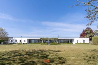 www.egaalstraat26.be<br />In ’95 werd een weldoordacht bouwplan uitgewerkt met licht en ruimte als uitgangspunt. Het resultaat, een eerder modernistische gelijkvloerse villa, te vinden in een bijzonder rustige straat in Kachtem. <br />Opgetrokken op een volledig zuidgericht perceel van 2.600m² in een agrarische omgeving met het pas aangelegde Vageweenbos om de hoek.<br /><br />De focus op de praktische indeling, met het leefgedeelte als ‘center’, maakt het wonen hier bijzonder aangenaam.<br />Quasi de volledige achtergevel bestaat uit hoge raampartijen met centraal een boog die rust en evenwicht creëert. Uniek is het koperen dak, specifiek gekozen om haar duurzaamheid, uitzonderlijke levensduur en weersbestendigheid.<br /><br />Al vanaf de inkomhal voel je je meteen thuis. De geautomatiseerde glazen tussenwand brengt je tot de XL doorloop-woonkamer met annex bureel, super gezellige TV hoek met (doorkijk)haard. Een halve wand scheidt de woonkamer van de praktisch ingerichte keuken met eetplaats, aansluitende berging, dubbele garage, technische berging en toilet.<br /><br />De linkerflank, gezien vanaf de inkomhal, bestaat uit een brede hal met toegang tot de masterbedroom met dressing en recent vernieuwde badkamer met o.a. een XL inloopdouche, Japans toilet, infrarood paneel. <br />De drie overige slaapkamers (14m², makkelijk moduleerbaar) maken gebruik van de tweede badkamer en extra toilet.<br /><br />De super onderhoudsvriendelijke tuin biedt rust en balans. Een strak gazon, serre, heerlijk ontspannen op de zonneterrassen, onder de schaduwrijke notelaars of het centrale terras overdekt met platanen.<br />Mogelijkheid om de aanpalende eigendom (op 4.000m²) eveneens bij te kopen.