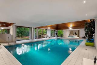 <strong>Verscholen in de natuur, in 1 van de mooiste lanen van Vriesdonk, rustig en residentieel: Architectenwoning op ca. 5.710 m². </strong><br /><br /><strong>De gelijkvloerse verdieping: </strong>- Een inkomhal op <strong>marmer </strong>met vestiaire, gootsteen en gastentoilet - Middels glazen deur naar woonkamer (ca. 70 m²) op vast tapijt met <strong>open haard,</strong> en schuiframen naar de <strong>tuin </strong>en <strong>overdekt terras </strong>- Een verlaagd <strong>zithoek </strong>(ca. 12 m²) op vast tapijt, eveneens met open haard - Een aanpalende <strong>bar </strong>(ca. 16 m²) - Een ruim bureau (ca. 29 m²) op parket, eveneens met schuiframen naar de tuin - Een eetkamer (ca. 25 m²) eveneens op marmer - Een keuken (ca. 20 m²) met <strong>inbouwtoestellen </strong>- Een aanpalende verhoogde <strong>ontbijthoek </strong>(ca. 4 m²) op vast tapijt - Een <strong>bijkeuken</strong> (ca. 8 m²) met dubbele gootsteen en aansluiting voor wasapparatuur - Een <strong>dienstingang</strong> met ingemaakte kasten, lavabo, apart toilet en douchekamer - Via dienstingang naar een ruime kelder bestaande uit <strong>wijnkelder</strong>, berging en technische kelder - Een <strong>polyvalente ruimte</strong>/<strong>snookerkamer </strong>met schuifraam naar de tuin - Een Een <strong>poolgedeelte</strong>/<strong>wellness </strong>met <strong>binnenzwembad </strong>(12 m op 6m) + jetstream, chloor, roldek alsook 2 <strong>kleedkamers</strong>, toilet, berging, douchekamer, technische berging, sauna, lavabo, <strong>bar </strong>met gootsteen, zitgedeelte met<strong> open haard </strong>en toegang naar de tuin - Een<strong> aparte dubbele garage</strong> (ca. 42 m²). <br /><br /><strong>De split-level verdieping: </strong>- Een ruime <strong>dressing </strong>(ca. 26 m²) op vast tapijt met ingemaakte kasten - Een apart toilet - Een eerste slaapkamer (ca. 20 m²) met aanpalende zithoek (ca. 17 m²) en berging (mogelijkheid voor extra slaapkamer) - Een badkamer (ca. 17 m²) met dubbele gootsteen, ingemaakte kasten, douche, ligbad en bidet.<br /><br /><strong>De eerste verdieping: </strong>- Boven de woonkamer: een tweede slaapkamer (ca. 32 m²) met ingemaakte kasten en eigen badkamer (ca. 5 m²) met ligbad, gootsteen en apart toilet - Boven de <strong>polyvalente ruimte</strong>: een derde slaapkamer op vast tapijt met ingemaakte kasten en Velux-raam - Boven de dienstingang: een vierde slaapkamer (ca. 12 m²) op vast tapijt. <br /><br /><strong>Algemeen: </strong>- <strong>Binnentuin</strong>, <strong>overdekt</strong> <strong>terras</strong>, diverse <strong>vijverpartijen</strong>, <strong>buitenbarbecue</strong>, <strong>professionele golf</strong> (putting green) - <strong>Rolluik </strong>in de eerste slaapkamer - Mogelijkheid voor <strong>conciërgerie</strong> i.v.m. dienstingang en apart "conciërge-gedeelte" - Verwarming op gas d.m.v. vloerverwarming (Remeha) en 2 boilers (ACV) - Bouwjaar 1971 en renovatie in 1995 (polyvalente ruimte en binnenzwembad,...) - Ruimtedetectie (alarm) is vernieuwd in 2022