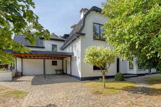 Instapklare, maar op te frissen villa met veel potentieel en uitzonderlijke ligging op mooi perceel(18a14). Omwille van de grote bewoonbare oppervlakte(350m2) en aparte indeling kan deze eigendom bewoond worden als gezinswoning, kangoeroewoning of gebruikt worden voor een vrij beroep in combinatie met woonst.<br /><br />Het goed werd door de jaren verbouwd/uitgebreid(steeds met vergunning). In 1987 werd de leefruimte rechts vergroot, in 1997 werd aan de achterzijde een extra leefruimte met slaapkamer en badkamer toegevoegd en in 2003 werd de eerste verdieping(houten buitengevel) uitgerust met een extra slaapkamer.<br /><br />Momenteel bestaat de woning uit: een inkomhal, ruime leefruimte (met bar, zithoek en openhaard), een bureau, ruime berging, uitgeruste hedendaagse keuken met doorgang tot het overdekt terras voorzien van buitenkeuken, tweede leefruimte en badkamer op het gelijkvloers. Op de eerste verdieping bevinden zich 6 slaapkamers( de meeste met sanitair), een tweede badkamer en apart toilet.<br /><br />Verder beschikt deze woning over een ruime tuinberging, een kelder, een carport voor twee wagens en een afgewerkte zolder. De woning is uitgerust met zonnepanelen, centrale verwarming (condesatieketel op aardgas) en op één van de slaapkamers is airco voorzien.<br /><br />We werken met een vanaf prijs waarbij alle biedingen mogelijk zijn en aan de eigenaar voorgelegd worden.<br /><br />Voor meer informatie of een bezoek ter plaatse –> ken@immovos.be of 0477/ 29 72 50