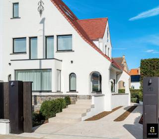 Op een uitmuntende locatie te Duinbergen, op een zucht van het strand en de duinen, bevindt zich deze hoogwaardig gerenoveerde koppelvilla. De eigendom combineert een ideale ligging (wandelafstand van strand) met een afwerkingsgraad die getuigt van oog voor detail en modern comfort. <br /><br />Indeling: Bij het binnenkomen wordt u verwelkomd in een elegante inkomhal die de sfeervolle zithoek aan de straatzijde scheidt van de open leefkeuken aan de tuinzijde. Deze keuken is verfijnd afgewerkt met eiken fineer en volledig uitgerust met kwalitatieve toestellen en dubbele ovens. De villa beschikt over vijf volwaardige slaapkamers, allen voorzien van riante maatkasten. De master suite geniet van een luxueuze ensuite badkamer met ligbad, inloopdouche en toilet; daarnaast zijn er nog drie extra badkamers aanwezig. <br /><br />Airconditioning en elektronische rolluiken garanderen een optimaal wooncomfort. De woning is volledig onderkelderd en beschikt over een garage met een extra douche, ideaal na een dag aan zee. Op het eigen terrein is parkeergelegenheid voor 4 à 5 wagens. Technisch is de villa uitgerust met nieuwe aluminium ramen, een alarmsysteem en een regenwaterput. <br /><br />Een ideale pied-à-terre voor de hele familie een absolute toplocatie.