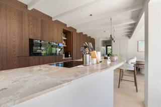 In een rustige, doodlopende straat , op slechts enkele minuten van het centrum van Knokke, bevindt zich deze uitzonderlijk gerenoveerde vrijstaande woning. Als voorlaatste woning in de straat geniet U hier van maximale privacy, een oase van rust en tegelijk een uitstekende bereikbaarheid van winkels, scholen, horeca en alle dagelijkse voorzieningen.<br /><br />Deze woning werd volledig op maat ontworpen voor comfortabel wonen, waarbij elk detail zorgvuldig werd uitgewerkt. Geen standaard renovatie, maar een doordacht totaalconcept waarin hoogwaardige materialen, verfijnde afwerking en praktisch wooncomfort harmonieus samenkomen. Doorheen de volledige woning werden maatwerkkasten geïntegreerd, subtiele indirecte verlichting accentueert de architectuur en zelfs de kleinste details, zoals discreet weggewerkte stopcontacten, dragen bij aan de luxueuze uitstraling. Op maat gemaakte gordijnen en de clay-stucafwerking over de volledige woning vervolledigen het geheel.<br /><br />Bij het betreden van de woning wordt U verwelkomd in een royale inkomhal met een indrukwekkende plafondhoogte. Een stijlvolle vestiairekast op maat, indirecte wandverlichting, een elegante gietvloer en een gastentoilet zetten onmiddellijk de toon.<br /><br />De leefruimte baadt dankzij de plafondhoge raampartijen in natuurlijk licht. Binnen en buiten vloeien naadloos in elkaar over, waardoor een bijzonder aangenaam ruimtegevoel ontstaat. De warme parketvloer en de op maat gemaakte kastenwand, die harmonieus doorloopt van de woonkamer naar de keuken, zorgen voor een strak en tijdloos interieur.<br /><br />De keuken vormt zonder twijfel het kloppende hart van de woning. Het organisch gevormde kookeiland met luxueus marmeren werkblad nodigt uit om samen te koken, aperitieven of gezellig aan de bar te ontbijten. De lichte clay-stucafwerking vormt een stijlvol contrast met de donkere maatwerkkasten en creëert een hedendaagse, verfijnde sfeer. Aansluitend bevindt zich de lichtrijke eetplaats met een prachtig zicht op de tuin.<br /><br />Praktisch comfort ontbreekt evenmin. Naast de keuken bevindt zich een volledig ingerichte wasruimte met maatwerkkasten, aansluitingen voor wasmachine en droogkast en een afzonderlijke zij-ingang. De inpandige garage biedt plaats aan een wagen en beschikt bovendien over extra ruimte voor fietsen, bromfietsen of bijkomende stockage. Ook op de oprit is er parkeergelegenheid voorzien voor twee wagens.<br /><br />De onderhoudsvriendelijke tuin werd aangelegd met oog voor rust en esthetiek. Het organisch gevormde natuurstenen terras vormt een verlengstuk van de leefruimte en biedt de ideale setting om in alle privacy van het buitenleven te genieten.<br /><br />Op de eerste verdieping bevindt zich de stijlvolle masterbedroom met maatwerkkasten en de ensuite badkamer beschikt over een ligbad, inloopdouche, wastafel en toilet. <br /><br />Daarnaast zijn er nog twee volwaardige slaapkamers die beiden toegang hebben tot een badkamer met inloopdouche, wastafel alsook een afzonderlijk toilet. <br /><br />Deze instapklare woning combineert hedendaagse architectuur, hoogwaardige materialen en een bijzonder doordachte indeling tot een unieke woonervaring. Een eigendom waar design, comfort en functionaliteit elkaar perfect versterken.<br /><br />Bent U op zoek naar een exclusieve woning waar rust, luxe en wooncomfort centraal staan, op een toplocatie nabij het centrum van Knokke? Contacteer ons vandaag nog voor meer informatie of plan een bezoek en laat u ter plaatse overtuigen door de uitzonderlijke afwerking en het unieke karakter van deze prachtige eigendom.