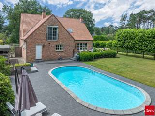 <p>Een charmante, energiezuinige villa met zwembad en indrukwekkend houten poolhouse in het groen van Zoersel</p>
<p>In een rustige, doodlopende straat in Zoersel, verscholen tussen het groen, bevindt zich deze bijzonder charmante woning die uitblinkt in ruimte, licht, comfort en privacy. Dankzij de uitstekende ligging geniet u hier van absolute rust en een groene omgeving, terwijl het centrum, scholen en alle voorzieningen vlot bereikbaar blijven.</p>
<p>Bij het betreden van de woning wordt u meteen omarmd door een warme en uitnodigende sfeer. Een lichte inkomhal met gastentoilet en vestiarekast verwelkomt u in deze charmante woning. De ruime leefruimtes genieten dankzij de grote raampartijen van een overvloed aan natuurlijk licht en staan in directe verbinding met de prachtig aangelegde tuin met zwembad en meerdere terrassen. De combinatie van hoogwaardige materialen, warme accenten en een doordachte indeling zorgt voor een bijzonder aangename woonbeleving.</p>
<p>De woonkamer vormt samen met de eetruimte het hart van de woning en beschikt over een sfeervolle gashaard, die zorgt voor extra warmte en gezelligheid tijdens de koudere maanden. De volledig ingerichte keuken sluit hier harmonieus op aan en biedt alle comfort voor dagelijks gebruik en gezellige momenten met familie en vrienden.</p>
<p>Een elegante houten trap met een prachtige vide leidt u naar de eerste verdieping waar de slaapkamers zich bevinden. De woning beschikt over een ruime mastersuite met een royale dressing en een stijlvolle badkamer, waardoor een echte privé-oase ontstaat. Daarnaast zijn er drie zeer ruime kinderkamers. Eén van deze kamers geniet dankzij de rechtstreekse verbinding met een volledig ingerichte zolderverdieping over een unieke extra ruimte, ingericht als een echte droomstudio voor elk kind. De kinderen beschikken bovendien over een aparte, ruime badkamer, uitgerust met een bad, inloopdouche, lavabo en toilet.</p>
<p>Verder beschikt de woning over een ruime waskamer, een praktische garage voor één wagen en een carport, waardoor ook op praktisch vlak aan alle comfort werd gedacht.</p>
<p>De zonnige, volwassen tuin met zwembad biedt volledige privacy en vormt de ideale setting voor lange zomeravonden, gezellige diners of ontspannen momenten met familie en vrienden.</p>
<p>Een absolute blikvanger van deze eigendom is het indrukwekkende houten poolhouse in de tuin. Dit stijlvolle bijgebouw vormt een volwaardige tweede leefruimte en is uitgerust met een gezellige zitruimte met kachel, een sfeervolle bar, een aparte bureauruimte, een sauna, douche en toilet. Hierdoor biedt het poolhouse een uitzonderlijke flexibiliteit: van ontspannings- en wellnessruimte tot volwaardige werk- of gastensuite. In combinatie met het zwembad, de zonnige terrassen en het omliggende groen ontstaat hier een unieke buitenbeleving met een permanent vakantiegevoel in eigen tuin.</p>
<p>Ook op vlak van energiezuinigheid scoort deze woning uitstekend dankzij de talrijke zonnepanelen, goed voor een gunstig EPC-label B, waardoor hedendaags comfort perfect gecombineerd wordt met duurzaam wonen.</p>
<p><strong>Bijzonderheden</strong></p>
<ul>
<li>Zee van ruimte en uitzonderlijke lichtinval</li>
<li>Prachtig aangelegde tuin met zwembad</li>
<li>Imposant houten poolhouse met wellness- en leeffaciliteiten</li>
<li>Energiezuinig wonen met EPC-label B</li>
<li>Aanzienlijke zonnepaneleninstallatie (PV)</li>
<li>Asbestvrij</li>
</ul>
<p>Kortom: een uitzonderlijk charmante en energiezuinige villa waar ruimte, licht, natuur en luxe buitenbeleving samenkomen. Een unieke thuis voor wie op zoek is naar rust, privacy en een hoogwaardige woonomgeving in het groene Zoersel.<br /><br />Voor meer informatie of bezoek aan deze gezellige woning neem contact met Sigalit via sigalit@reds.be of op 0475668474</p>