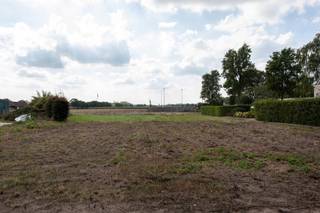 <p>Ontdek deze mooie bouwgrond voor een halfopen bebouwing, goed georiënteerd en genietend van een weids, landelijk uitzicht. Het perceel laat een ruime gezinswoning toe met een bouwvolume van maximaal 9 x 15 m op het gelijkvloers en 9 x 13 m op de verdieping, aangevuld met een tweede bouwlaag onder het dak. Zowel een moderne woning met plat dak als een klassieke uitvoering met hellend dak zijn mogelijk, met een maximale nokhoogte van 11 m en kroonlijsthoogte van 6,50 m. Een gekoppelde oprit met inpandige garage is verplicht, terwijl achteraan een vrijstaand bijgebouw tot 40 m² kan worden opgericht. De totale verhardingsoppervlakte op het perceel is beperkt tot 70 m², waardoor het groene karakter optimaal behouden blijft. Een unieke kans om uw droomwoning te realiseren op een centrum locatie met blijvend open zicht.</p>