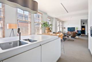 Dit appartement op de tweede verdieping is een modern pareltje in het hart van de stad, bereikbaar via lift of authentieke trap.
Bij binnenkomst valt meteen de lichtrijke leefruimte op, dankzij grote raampartijen en hoge plafonds. Alle ramen zijn voorzien van kwalitatieve jaloezieën in lichte walnoot, wat zorgt voor warmte en privacy. Aansluitend bevindt zich de exclusieve Bulthaup-keuken met kookeiland en hoogwaardige toestellen: combi-oven, inductiekookplaat met design dampkap (Venduro), vaatwasser, koelkast, aparte vriezer en wijnkoeler.
Verder is er een praktische berging met aansluiting voor was- en droogmachine, een vestiaire en een apart gastentoilet.
De eerste slaapkamer beschikt over een ensuite badkamer en dressing. Daarnaast zijn er nog twee volwaardige slaapkamers, waarvan één ingericht als bureauruimte, en een tweede stijlvolle badkamer.
In de kelder vindt u een privatieve berging en fietsenstalling. Het appartement is uitgerust met lift, videofonie, een condenserende gasketel en een warmwaterboiler van 160 liter.
Gelegen op een toplocatie in de Theaterwijk, omringd door winkels, theaters en supermarkten. Vlotte verbinding via de Leien en parkeermogelijkheden vlakbij.