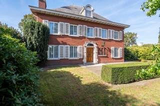<p>Aan de rand van Hoogstraten bevindt zich deze statige villa, op wandelafstand van het centrum, winkels en horecazaken. De woning combineert royale ruimtes en karaktervolle elementen met een prachtig zicht op de groene tuin, waar u in alle rust en privacy kunt genieten.</p>
<p>Via de ruime inkomhal met gastentoilet en vestiaire komt u in de imposante traphal. Verder vindt u hier een bureel met ingemaakte kasten en een sfeervolle woonkamer met open haard. Grote raampartijen bieden een aangenaam uitzicht op de tuin. Ook de leefkeuken kijkt uit op het groen en is uitgerust met een Aga-fornuis en tal van ingemaakte kasten. Aansluitend bevinden zich een praktische bijkeuken met wasplaats en een extra vestiaire, met rechtstreekse toegang tot de tuin. In het bijgebouw bevindt zich bovendien een ruimte voor huishoudelijke apparaten, bereikbaar via een tussenruimte. De garage biedt plaats aan twee wagens achter elkaar. Via een vlizotrap bereikt u vanuit de garage de zolder.</p>
<p>Op de eerste verdieping bevinden zich vijf ruime slaapkamers en één kleinere kamer, evenals een badkamer. De kleinere kamer biedt de mogelijkheid om een tweede badkamer in te richten. Een vaste trap leidt naar de zeer ruime zolder, die gedeeltelijk geïsoleerd is.</p>
<p>De woning beschikt over ruime kelders met een goede plafondhoogte, waaronder een provisiekelder, wijnkelder en stookkelder met mazoutverwarming. Achteraan strekt zich een diepe, westelijk georiënteerde tuin uit, met prachtige bomen en veel privacy. Dankzij de volwassen beplanting geniet u hier in alle rust, zonder inkijk van de buren.</p>
<p>Een karaktervolle villa met veel ruimte, praktische aanhorigheden en een uitzonderlijke tuin, op een bijzonder gunstige locatie nabij het centrum van Hoogstraten.</p>
<p>De woning is gelegen aan de Lodewijk De Konincklaan in Hoogstraten, op een gunstige locatie vlak bij het centrum. De levendige winkelstraat De Vrijheid, met haar gevarieerd aanbod aan winkels, speciaalzaken en horeca, bevindt zich op korte afstand. VisitHoogstraten</p>
<p>Ook op het vlak van bereikbaarheid is de ligging bijzonder praktisch. Hoogstraten heeft een vlotte aansluiting richting de E19 Antwerpen–Breda, terwijl station Noorderkempen in Brecht en verschillende busverbindingen bijkomende mogelijkheden bieden voor het openbaar vervoer.</p>
