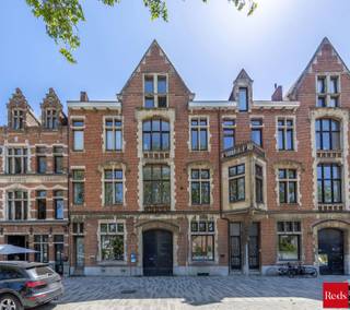 <p>Uniek herenhuis met zuidtuin, zwemvijver en veelzijdig karakter op absolute toplocatie.</p>
<p>Met veel enthousiasme presenteren wij dit uitzonderlijke herenhuis aan de Vlaamsekaai, ongetwijfeld één van de meest gegeerde locaties van Antwerpen-Zuid. Deze riante woning in rijke, pittoreske neo-Vlaamse-renaissance stijl werd in 1879 ontworpen door de vermaarde architect J.V. Delpierre in opdracht van de Waalse baron de Senzeille. Een heus stukje Antwerpse geschiedenis dus, aan de mooiste hoek van het populaire Zuidpark én pal in het hart van de meest bruisende buurt. Toch schuilt er achter de statige gevel een oase van stilte en achter de elektrische poort een prachtige, heerlijk rustgevende tuin waar u onmiddellijk de drukte van de stad afschudt en zich meteen in de Provence waant.</p>
<p>Het ruime gelijkvloers met enkele originele elementen én hoge plafonds is vergund als commerciële ruimte en momenteel ingericht als galerij met mezzanine. Achterin is er een recent vernieuwd badkamertje met douche, toilet en lavabo. Deze etage is dus ideaal als praktijkruimte, showroom en atelier, of voor specialisten of vrije beroepen die wonen en werken willen combineren op een zeer commerciële locatie.</p>
<p>Een plafondhoge glazen deur geeft uit op de onvolprezen blikvanger: de fraaie tuin met zwemvijver van net geen tien meter lengte. Het is een biologische zwemvijver: dus géén chloor of chemicaliën, wel zuiver, heerlijk verfrissend water. Een zeldzame troef op deze locatie. Onmogelijk om tegelijk in de stad én op de buiten te wonen? Wellicht wel, al komt dit wel zeer dichtbij dat unieke gevoel.</p>
<p>De indrukwekkend ruime én hoge kelder kan fungeren als opslag, wijnkelder, hobbyruimte of praktische stockage. Hij doet momenteel dienst als magazijn voor boeken. Achterin is er tevens een kleine keuken met daglicht, gas en water.</p>
<p>De authentieke traphal ademt grandeur en elegantie, terwijl een tweede binnentrap de verschillende leefruimtes en tussenverdiepingen met elkaar verbindt. De eerste etage bestaat uit twee royale bureaus met originele eiken vloeren, houten deuren en zicht op de tuin of het park. Er is eveneens een praktische bijkeuken en wasruimte.</p>
<p>Beide slaapkamers op de tweede verdieping ademen elk een eigen sfeer. De master bedroom aan de achterzijde is zeer stil, kijkt uit op de tuin, beschikt over airconditioning en een recent vernieuwde ensuite badkamer met lavabo, toilet en een goed toegankelijke inloopdouche. De zeer ruime slaapkamer vooraan heeft opnieuw een authentieke eiken vloer én zicht op het Zuidpark. De aansluitende dressing baadt dankzij de mooie raampartij ’s avonds in prachtig zonlicht. Een huis waar je zowel voor als achteraan van bomen, natuur en vrolijk zingende vogeltjes kan genieten: ook dit blijft uiterst zeldzaam in de stad.</p>
<p>Het pas gerenoveerde, lichtrijke en volledig geïsoleerde leefgedeelte op de bovenste verdieping heeft airconditioning en sluit aan op de onlangs gerenoveerde keuken. Dankzij een kamerbrede schuifdeur lijken woonkamer en het aangename, zuidgerichte terras wel één geheel. Het terras baadt in rust en kijkt uit op de paarden bovenop het KMSKA.</p>
<p>De woning beschikt over dubbele beglazing in hardhouten raamprofielen en combineert authentieke charme met hedendaags wooncomfort. Dit uitzonderlijke, zeer ruime pand op een absolute toplocatie in Antwerpen-Zuid is vooral erg flexibel en daarom zowel interessant als investering of als woning. Met zijn drie boilers en drie digitale meters en vele nutsvoorzieningen kan het relatief eenvoudig worden opgedeeld in appartementen. Het kan eveneens dienen als gastenkamers, wellness of voor mensen met een vrij beroep die wonen en werken willen combineren. Parkeren is géén probleem. Recht over de deur ligt onder het park een giga parkeergarage met zeer voordelige voorwaarden voor bewoners.</p>
<p>Voor meer informatie of een persoonlijke rondleiding kan u contact opnemen met Amparo op +32 478 68 29 86 of via amparo@reds.be.</p>