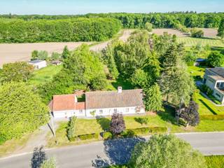 <p>Een oase van rust, omringd door open velden en groen. Deze karaktervolle 19de-eeuwse woning combineert authentieke charme met hedendaags comfort én tal van mogelijkheden voor wonen en werken.</p>
<p></p>
<p>Op een prachtig perceel van 1.831 m² geniet je van een mooie, ruime tuin met volwassen bomen en veel groen. Dankzij de grote ramen en de mooie verbinding tussen binnen en buiten geniet je ook vanuit de woning volop van het omliggende landschap.</p>
<p></p>
<p>Met een bewoonbare oppervlakte van 265 m² is ruimte hier absoluut geen probleem. De woning beschikt over 3 slaapkamers, met de mogelijkheid om dankzij de aanwezige bureau-/praktijkruimtes uit te breiden tot 5 slaapkamers. Ideaal voor wie een combinatie zoekt van privé wonen en een zelfstandige activiteit, praktijk of kantoor aan huis.</p>
<p></p>
<p>De rustieke elementen in de woning zorgen voor een unieke knipoog naar het verleden, terwijl het nodige hedendaagse comfort aanwezig is. Verder beschikt de woning over een carport en is er voldoende parkeergelegenheid voor de deur.</p>
<p></p>
<p>De woning beschikt momenteel over een minder gunstige EPC-score, wat uiteraard mogelijkheden biedt voor wie de woning verder energetisch wil optimaliseren en naar eigen smaak wil vernieuwen.</p>
<p></p>
<p>De indeling is als volgt:</p>
<p>Het gelijkvloers voorziet in een inkomhall met toegang naar de leefruimte, keuken en bureau. Verder vind je de badkamer (met ligbad en douche) en apart toilet. De doorgang naar het praktijdgedeelte geeft uit op de praktijk met twee bureau’s (1 per niveau).</p>
<p></p>
<p>De verdieping bestaat uit de nachthall, drie slaapkamers en een tweede toilet.</p>
<p></p>
<p>Buiten vinden we de tuinberging, een ruim tuinhuis en een carport.</p>
<p></p>
<p>Een unieke woning voor wie op zoek is naar karakter, ruimte, groen en vooral… een uitzonderlijk rustige ligging!</p>
<p></p>