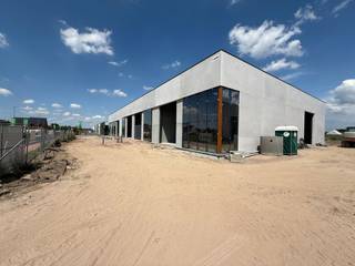 Ruime KMO-unit of showroom van 276 m² met 3 eigen parkeerplaatsen. Deze unit is ideaal voor bedrijven die een zichtlocatie zoeken om hun onderneming te profileren. Gelegen in Dentergem, centraal in de driehoek Tielt-Deinze-Waregem, profiteert deze locatie van een uitstekende bereikbaarheid en visibiliteit. Het magazijn heeft een vrije hoogte van 6 meter en beschikt over kwaliteitsvolle voorzieningen, zoals een lichtstraat met RWA-koepel en grote raampartijen, wat niet alleen de werkruimte aangenaam maakt, maar ook een perfecte gelegenheid biedt om een mezzanine in te bouwen voor extra kantoor- of showroomruimte.<br /><br />De unit wordt casco opgeleverd en maakt deel uit van de vierde fase van de prestigieuze<strong> KMO-ontwikkeling "RIVA."</strong> Deze nieuwe ontwikkeling omvat vier fasen en in totaal 26 units/showrooms, met oppervlaktes van 200 m² tot 373 m², en biedt mogelijkheden tot samenvoeging voor een ruimte van maar liefst 1.850 m². De loodsen zijn perfect geschikt voor uiteenlopende activiteiten, van opslag en productie tot commerciële toepassingen, waardoor ondernemers veel flexibiliteit hebben.<br /><br />Er is verder ook een mogelijkheid om in overleg zonnepanelen of laadpalen te plaatsen. Voor iedere unit zijn <strong>privatieve parkeerplaatsen</strong> voorzien, wat handig is voor zowel personeel als bezoekers.<br />Contacteer <strong>PANORAMA B2B</strong> voor gedetailleerde informatie, bouwplannen, of om een vrijblijvend bezoek te plannen via het nummer <strong>0477 02 09 02</strong>.