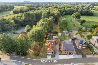 Voor meer info en foto’s, surf naar www.swevers.be – Oude Baan 39 in Heusden-Zolder biedt een unieke kans voor wie een woning volledig naar eigen smaak wil renoveren of herontwikkelen. De open bebouwing uit 1955 ligt op een uitzonderlijk ruim perceel van 36a05. De perceelsbreedte bedraagt ongeveer 18 meter, waardoor een gevelbreedte van circa 12 meter tot de mogelijkheden kan behoren, uiteraard onder voorbehoud van vergunningen. Bij afbraak en heropbouw kan onder de toepasselijke voorwaarden bovendien een btw-tarief van 6% gelden in plaats van 21%. Dit is een bijzonder financieel voordeel. Een opportuniteit om uw woning waar te maken. Denk maar aan een knappe uitbouw met grote raampartijen richting de tuin die het groen volledig naar binnen halen. De grote troef is het perceel met veel groen, een gedeeltelijk bebost karakter en ruimte voor dieren. Achteraan grenst het terrein aan agrarisch gebied, met uitzicht op weilanden en groen. Winkels liggen op ca. 1,3 km, scholen op ca. 2 km en de snelweg op ca. 6 km. Een eigendom voor wie ruimte, rust en toekomstmogelijkheden zoekt. Voor meer informatie, bel 011 255 155. Bron bewoonbare oppervlakte: EPC – verslag. Dit pand is onderworpen aan de renovatieverplichting van de Vlaamse overheid voor residentiële gebouwen (behoudens bij sloop binnen 5 jaar na de aankoop). Consulteer voor meer informatie de website van het Vlaams Energie- en Klimaatagentschap via https://www.vlaanderen.be/een-huis-of-appartement-kopen/renovatieverplichting-voor-residentiele-gebouwen.