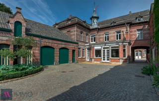 Deze neoclassicistische herenwoning anno 1868 met dubbelhuisopstand, de voormalige brouwerswoning van de brouwerij Du Bois-Haems, is gelegen in hartje Lebbeke, temidden van de driehoek Brussel-Gent-Antwerpen. Het interieur bevat talloze decoratieve elementen, waaronder een salon in Lodewijk XVI-stijl, mozaïekvloeren, stucplafonds, marmeren schouwen,...Dit pareltje heeft een parktuin van 59 are 51 ca met vijver, Lourdesgrot, antiek zwembad en talrijke imposante bomen waaronder een bruine beuk en linden. Deze indrukwekkende woning heeft een zeer ruime leefruimte (94 m²) met 3 schouwen en een leefkeuken (51 m²) met oa een AGA-fornuis, op de verdieping zijn er onder andere 7 slaapkamers en 2 badkamers. Naast de 2 garages, de wijnkelder, de paardenstallen en een gastenverblijf is er een inrijpoort met automatische poort en een met kasseien nieuw aangelegde binnenkoer. Alle technieken werden recentelijk vernieuwd (centrale verwarming op aardgas, riolering, elektriciteit), alsook de leefkeuken en de 2 badkamers met Old English douche,ligbad en wastafels. Deze woning is beschermd als monument, waardoor U kan aankopen onder het gunstig stelsel van 1% registratiekosten op voorwaarde dat de woning als gezinswoning wordt aangewend én dat er investeringen worden gedaan aan het pand. Zoniet blijft de 5%-regel gelden. Het bekomen fiscaal voordeel wordt aanzien als een fictieve subsidie, waarbij de koper binnen de vijf jaar na zijn aankoop 6% van de aankoopprijs dient te investeren in onderhouds- of renovatiewerken van het pand. Zodoende zou de nieuwe eigenaar dus 7% van de aankoopprijs betalen, zijnde 1% registratierechten en 6% aan investeringen. U kan ook daarnaast ook genieten van restauratie-en of renovatiepremies. Meer info op: https://www.onroerenderfgoed.be/nl/premies/ EPC: 432 kWh/m²/j. en UC:2070674-RES-2