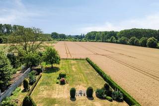 <br />Op een groene en ideaal gelegen locatie aan Melveren Centrum 68 staat deze vrijstaande gelijkvloerse woning op een perceel van 20 are. Het pand wordt grotendeels omringd door open velden, met achteraan een groen uitzicht. Privacy is hier vanzelfsprekend en gegarandeerd!.<br /><br />Ondanks de landelijke omgeving bevindt het centrum van Sint-Truiden zich vlakbij. De woning grenst aan het parochiecentrum en combineert een open ligging met winkels, scholen, openbaar vervoer en dagelijkse voorzieningen op korte afstand.<br />De zuidwestelijke oriëntatie zorgt de hele dag door voor natuurlijk licht. De volledig gelijkvloerse indeling maakt de woning toegankelijk en geschikt voor elke levensfase.<br /><br />De bewoonbare oppervlakte bedraagt circa 145 m². Aan praktische ruimte is er geen gebrek. Onder de woning ligt een kelderverdieping van circa 60 m², en op het perceel staat een vrijstaande garage van circa 45 m². Plaats voor meerdere voertuigen, een werkplaats of bijkomende bergruimte.<br /><br />De woning is uitgerust met drie airco-units, rolluiken rondom, een waterverzachter en houten ramen in afzelia met dubbele beglazing. Het dak werd geïsoleerd met 10 cm PUR. De centrale verwarming werkt op stookolie, met een Viessmann-ketel en radiatoren die in 2020 werden deels vernieuwd. Een zonneboiler met zonnepanelen voorziet het sanitair warm water, tot slot is er een alarmsysteem aanwezig.<br /><br />Het geheel vormt een degelijke en ruime basis die u verder naar eigen smaak kunt inrichten of moderniseren. De grootste troef blijft het perceel: circa 2.000 m² grond, een perceelbreedte van ongeveer 23 meter, zuidwest georiënteerd en omgeven door rust.<br /><br />Gelijkvloers wonen, ruimte in overvloed en groen rondom, met het centrum van Sint-Truiden binnen handbereik. Zo'n pand op dergelijk uniek perceel komt zelden vrij. Contacteer Aktimmo voor een verdere verkenning.