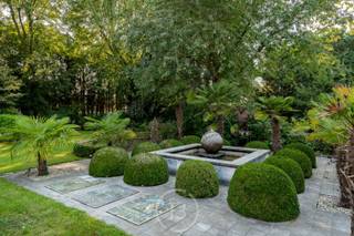 Deze unieke architectenvilla werd gebouwd in 1976 en ontworpen door architect Jan Vangheluwe. De totale oppervlakte van het perceel bedraagt ca. 6000 m² met een bewoonbare oppervlakte van maar liefst 1057 m². De villa wordt gekenmerkt door de afgeronde volumes en een prachtige groene tuin. De grote zaal biedt de mogelijkheid om burelen te voorzien. <br /><br />Bij het betreden van de villa komen we in een grote inkomhal met gastentoilet en vestiaire. <br />Centraal in de woning bevindt zich de keuken, met berging en koelcel, die geniet van een mooi zicht over de tuin. Aansluitend is er de eetplaats met woonkamer die toegang biedt aan het terras. <br />Verder vinden we drie ruime kinderslaapkamers met bureel, een ruime badkamer, een logeerkamer met eigen badkamer, een royale masterbedroom met dressing en badkamer ensuite en een zeer praktische wasplaats.<br />De eerste verdieping omvat een ruimte die omgetoverd kan worden naar een hobbyruimte of extra slaapkamer.<br />Tenslotte is er nog een enorme polyvalente ruimte van maar liefst 200 m² die kan dienen als kantoorruimte, vergaderzaal, receptiezaal… <br /><br />Extra troeven <br />-Dubbele garage <br />-Ruime kelder <br />-Mogelijkheid tot uitoefenen van vrij beroep <br />-Veel parkeergelegenheid op perceel