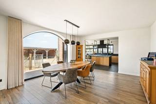 Deze stijlvolle woning is gebouwd in 2020 en is afgewerkt met kwalitatieve en duurzame materialen. Deze eigendom beschikt over een sfeervolle woonkamer, lichte leefkeuken, wasplaats, 4 slaapkamers op de 1e verdieping, bureau of 5e slaapkamer op de gelijkvloerse verdieping, badkamer, 2e nog af te werken badkamer, dressing en dubbele carport met overdekt terras. <br />De villa is gelegen op een groen domein met vrij uitzicht op omliggende weilanden. Hier geniet u van ruimte en rust op een interessante locatie vlakbij de Nederlandse grens. <br /><br />Gelijkvloers:<br />U betreedt de woning via de ruime inkomhal met apart toilet. Hierlangs heeft u toegang tot de sfeervolle woonkamer op tegelparket dat via de grote ramen achteraan uitzicht geeft op de open tuin. De moderne leefkeuken met groot eiland en natuurstenen werkblad is voorzien van kwalitatieve toestellen (inductievuur, combi oven/micro, oven, warmhoudlade, vaatwasmachine, koelkast). De wasplaats is toegankelijk via een ingewerkte deur in de keuken wat voor een strak geheel zorgt. Vooraan de woning bevindt er zich nog een bureauruimte of extra gelijkvloerse slaapkamer afgewerkt met een prachtige visgraatparkettegel.<br /><br />Eerste verdieping:<br />De bovenverdieping is eveneens uitgerust met parket en is opgedeeld in 4 slaapkamers waarvan de masterbedroom voorzien is van een dressing en eigen badkamer. Verder bevindt er zich nog een afzonderlijk toilet en tweede badkamer die nog verder naar eigen smaak af te werken is. <br /><br />Tuin:<br />In de tuin is het aangenaam vertoeven door het weidse uitzicht. De tuin is voorzien van een ruim bijgebouw waar plaats is voor meerdere wagens en ook gebruikt kan worden als overdekt terras. Doordat het perceel ca. 6.886m² is, bestaat de mogelijkheid dieren te houden.<br /><br />Bijzonderheden:<br />- Ruim perceel met open zichten<br />- Instaklare woning met kwalitatieve afwerking<br />- Regenwaterput aangesloten op toiletten en wasmachine <br />- 2 geboorde grondwaterputten van 12m diepte<br />- Energiezuinige woning (E30) met zonnepanelen en vloerverwarming <br />- Alarm en domotica