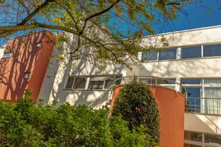 <p><strong>Uitzonderlijk </strong><strong>vastgoed, een architecturaal ensemble </strong><strong>- </strong>In het hart van de Antwerpse binnenstad bevindt zich dit opmerkelijke eigendom, verscholen achter een rustige kasseienstraat en omringd door historische gevels. Een zeldzame combinatie van architecturale expressie, stadse rust en groene geborgenheid.</p>
<p>Het residentieel complex onderscheidt zich door zijn eigenzinnige architectuur. De zorgvuldig ontworpen gevel integreert zich op harmonieuze wijze in de historische stadsomgeving. Strakke witte volumes met horizontale raampartijen, een aansprekend samenspel van baksteen, glas en beton.</p>
<p>Een ruime en lichtrijke duplex met vier slaapkamers. Het appartement biedt alle comfort voor een gezin of voor wie ruimte en flexibiliteit centraal stelt. Het grote terras, dat naadloos aansluit op de tuin, vervaagt de grens tussen binnen en buiten en creëert een bijzondere woonomgeving in de binnenstad.</p>
<p><strong>Tuin</strong></p>
<p>Achter het gebouw ontvouwt zich een weelderige tuin – een uniek bezit in de historische binnenstad. De tuin, aangelegd met grind, eeuwenoude bomen, geschoren hagen en bloemperken, grenst aan een schilderachtige historische muur met een gotische boogopening. Een plek van rust en groen, op wandelafstand van alle stedelijke voorzieningen.</p>
<p><strong>Troeven in het kort</strong></p>
<ul>
<li>Centrale ligging in de historische binnenstad</li>
<li>Verscheidene terrassen met uitzicht op de tuin</li>
<li>Groene binnentuin</li>
<li>Dubbele garagebox optioneel te koop aan 75.000 EUR</li>
</ul>