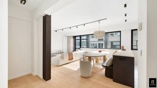 In het hart van het Zoute, discreet verscholen om de hoek van de Zeedijk en perfect gelegen tussen het Albertplein en het Driehoeksplein, bevindt zich dit volledig vernieuwde appartement met twee ruime slaapkamers. Een topligging waar licht, rust en zee samenkomen.<br /><br />Via de verzorgde inkomhal met vestiaire en gastentoilet betreedt u de royale leefruimte, die dankzij een uitzonderlijke gevelbreedte van maar liefst 7 meter baadt in het licht. De open, volledig uitgeruste keuken sluit hier naadloos op aan en is verfijnd afgewerkt met een travertin werkblad en hoogwaardige Miele-toestellen. Praktisch comfort is voorzien met een aansluiting voor wasmachine.<br /><br />De master bedroom straalt rust en elegantie uit, met maatwerk inbouwkasten en een privatief terras waar u een mooi zicht op zee geniet. Deze slaapkamer beschikt over een eigen badkamer. De tweede volwaardige slaapkamer is eveneens voorzien van ingemaakte kasten en heeft haar eigen douchekamer.<br /><br />Een private kelder en een gemeenschappelijke fietsenberging vervolledigen het geheel.<br /><br />Ook het gebouw zelf werd recent grondig vernieuwd: een nieuwe gevel, nieuwe terrassen met transparante balustrades, nieuwe ramen en een vernieuwde lift zorgen voor een hedendaagse uitstraling en extra wooncomfort. Gelegen op de vierde verdieping geniet het appartement het hele jaar door van een optimale zoninval.<br /><br />Een stijlvol en warm appartement, uitgevoerd in zachte zandtinten en duurzame materialen, op een steenworp van de Zeedijk van het Zoute.<br /><br />Optioneel: mogelijkheid tot aankoop van een garagebox in de Zoutelaan (Residentie Sun House – € 75.000).