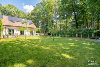 In het gegeerde Bois du Strihoux in Rebecq bevindt zich deze verzorgde villa op een perceel van 12 are 36 centiare. De ligging is bijzonder: het Bois du Strihoux maakt deel uit van het historische boscomplex Bos Ter Rijst – Bois du Strihoux, dat ooit ongeveer 360 hectare omvatte. Vandaag vormt deze groene residentiële omgeving een van de meest gewaardeerde woonzones van Waals-Brabant, met brede dreven, grote percelen, privacy en een rustige sfeer. Hier woont u midden in het groen, terwijl Halle, Tubeke, Edingen en Brussel vlot bereikbaar blijven.
Via de automatische toegangspoort bereikt u het afgesloten perceel. De tuin met volwassen bomen biedt zithoeken waar u in alle rust geniet van de groene omgeving. De verwarmde dual-zone swimspa met tegenstroominstallatie en de ruime jacuzzi vormen samen een exclusieve privéwellness. Dankzij de doordachte verwarmingsinstallatie blijven de gebruikskosten beperkt: het zwemgedeelte benut de energie van de zonnepanelen, terwijl het jacuzzigedeelte via een warmtewisselaar op de centrale verwarming wordt verwarmd.
Op het gelijkvloers bevinden zich de leefruimte met open haard, de eetplaats en de open keuken. Dankzij de schuifdeur kan het afzonderlijke salon worden afgesloten en ingericht als bureau, leeskamer of extra zithoek.
De eerste verdieping omvat drie ruime slaapkamers. Twee slaapkamers worden verbonden door een tussenliggende badkamer. Daarnaast is er een afzonderlijke douchekamer met toilet.
Ook de kelderverdieping biedt veel mogelijkheden. Hier bevindt zich een ruime homecinema of tv-zaal met grote raampartij en daglicht. De ruimte is voorbereid voor 5.1 surroundgeluid. Verder beschikt deze verdieping over een extra douchekamer en een ruimte voor hobby, fitness, speelkamer of praktijkruimte.
Met een bruto vloeroppervlakte van 276 m² combineert deze villa ruimte, comfort en energiezuinigheid. De 27 zonnepanelen van samen 11,1 kWp, de regenwaterput van 10.000 liter, het bekabelde datanetwerk met wifi-access points, de voorbereiding voor een 22 kW-laadpaal, vernieuwde sanitaire leidingen, de grotendeels vernieuwde elektrische installatie en energiezuinige radiatoren maken deze woning klaar voor de toekomst.
De ligging in het Bois du Strihoux, de verwarmde swimspa, de jacuzzi, de ruime leefruimtes, de technische uitrusting en het groene perceel maken van deze villa te koop in Rebecq een zeldzame opportuniteit voor wie rust, privacy, natuur, wellness en modern wooncomfort wil combineren.