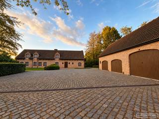 Droom je van landelijk wonen in alle rust, maar met een vlotte bereikbaarheid? Deze charmante hoeve in Anzegem, gelegen op een perceel van ca. 1,6 hectare, combineert karakter en ruimte met een prachtige groene omgeving. Dankzij de nabijheid van winkels, scholen en de E17 leef je hier in het beste van twee werelden.
<h3>Indeling van de woning</h3>
Bij het binnenkomen word je verwelkomd in een ruime inkomhal met gastentoilet en vestiaire. De gezellige leefruimte met houthaard sluit naadloos aan op de open, volledig uitgeruste leefkeuken. Verder zijn er een wasplaats en berging die zorgen voor heel wat extra opbergruimte.<br />De hoeve telt in totaal vijf slaapkamers, waaronder:
<ul>
<li>Een gelijkvloerse slaapkamer met eigen badkamer (inloopdouche, lavabomeubel en apart toilet). Ideaal als kangoeroewoning of gastenverblijf.</li>
<li>Vier slaapkamers op de eerste verdieping, waarvan één met lavabo en bad.</li>
<li>Een bijkomende badkamer met ligbad, lavabomeubel en toilet.</li>
</ul>
Daarnaast is er een bureau met ingebouwde kasten, een ruime droge kelder en een grote nachthal met extra opbergmogelijkheden.
<h3>Praktische troeven</h3>
<ul>
<li>3 garages met automatische poorten</li>
<li>Volledig onderkelderd met erboven een ruime zolder via vaste trap</li>
<li>Regenwaterput van 30.000 liter</li>
</ul>
<h3>Buitenleven op zijn best</h3>
De charme van deze eigendom zit niet alleen binnen. Buiten geniet je van een uitgestrekte tuin, een statige oprijlaan met twee poorten en een idyllische vijver. De serre biedt extra mogelijkheden voor tuinliefhebbers. Rechts van de hoeve ligt een grote weide, ideaal voor wie paarden of andere dieren wil houden. Omheining en stallen kunnen mee overgekocht worden.
<h3>Jouw stijl, jouw hoeve</h3>
Deze hoeve is instapklaar maar biedt tegelijk ook de kans om het interieur volledig aan te passen naar je eigen smaak en woonstijl. Zo maak je van dit ruime, solide gebouw een thuis die perfect aansluit bij jouw levensstijl.
<h3>Interesse? Vraag een bezoek aan</h3>
Vraag een bezoek aan via sarah@maesconceptimmo.be.<br />