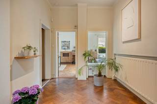 <p>Op een bijzonder fijne locatie in een aangename woonwijk, vlakbij het centrum van Dilbeek, bevindt zich deze karaktervolle architectenwoning uit het interbellum. De woning is een mooi voorbeeld van de architectuur uit die periode, waarin invloeden van art deco, traditionalisme en strak modernisme samenkomen. Opvallende volumes, ambachtelijk metselwerk, geometrische vormen en grote raampartijen geven de woning haar uitgesproken karakter en zorgen bovendien voor een overvloed aan natuurlijk licht. Heel wat authentieke elementen bleven mooi bewaard en worden vandaag gecombineerd met hedendaags wooncomfort.</p><p> </p><p>Achter de charmante gevel wordt u verwelkomd in een mooie inkomhal die meteen de authentieke sfeer en architecturale eigenheid van de woning weerspiegelt. Een apart toilet en een ruime centrale hal leiden naar de verschillende leefruimtes.</p><p>De royale leefruimte is een absolute blikvanger, met een prachtige parketvloer, veel natuurlijk licht en een warme uitstraling. Aansluitend bevindt zich de keuken met gezellige eethoek. Daarnaast beschikt de woning over een aparte bureauruimte en een vestiaire-/multifunctionele ruimte die naar eigen behoefte kan worden ingericht.</p><p>Vanuit de leefruimtes is er toegang tot het mooie terras en de heerlijke tuin. Een groene oase met veel privacy en verschillende gezellige hoekjes waar u op elk moment van de dag een aangename plek vindt om te ontspannen, te genieten of gasten te ontvangen.</p><p> </p><p>Op de eerste verdieping bevinden zich vier slaapkamers en een badkamer met zowel een douche als een ligbad. De hoofdslaapkamer heeft als extra troef een rechtstreekse toegang tot een groot terras, terwijl ook de slaapkamer aan de voorzijde toegang biedt tot een balkon.</p><p>De zolderverdieping biedt nog bijkomend potentieel en kan naar eigen wensen worden ingericht: een hobbyruimte, speelruimte of atelier behoren tot de mogelijkheden.</p><p>De woning is grotendeels onderkelderd en beschikt bovendien over een grote garage, wat zorgt voor praktische bergruimte.</p><p> </p><p>Ook energetisch werd de woning recent grondig aangepakt. Zo werden onder meer nieuwe ramen geplaatst, 18 zonnepanelen met batterij geïnstalleerd, het dak vernieuwd en geïsoleerd en een nieuwe gasketel geplaatst. Zo blijft het uitgesproken interbellumkarakter behouden, terwijl de woning tegelijk geniet van hedendaags comfort en een verbeterde energie-efficiëntie.</p><p>De authentieke architectuur vormt hier duidelijk de basis. Tegelijk biedt de woning ruimte om bepaalde vertrekken naar eigen smaak verder te verfijnen en te actualiseren. </p><p> </p><p>De ligging is bijzonder praktisch: op wandelafstand van het centrum van Dilbeek via fiets- en voetgangerstunnel en van winkels, scholen en openbaar vervoer. Tegelijk geniet u van de rust en het aangename karakter van een fijne woonwijk.</p><p>Een bijzondere architectenwoning met een uitgesproken interbellumkarakter, royale ruimtes en een prachtige parktuin. Een unieke combinatie van architecturale eigenheid, authenticiteit, ruimte en hedendaags wooncomfort, op een gegeerde locatie in Dilbeek.</p>
